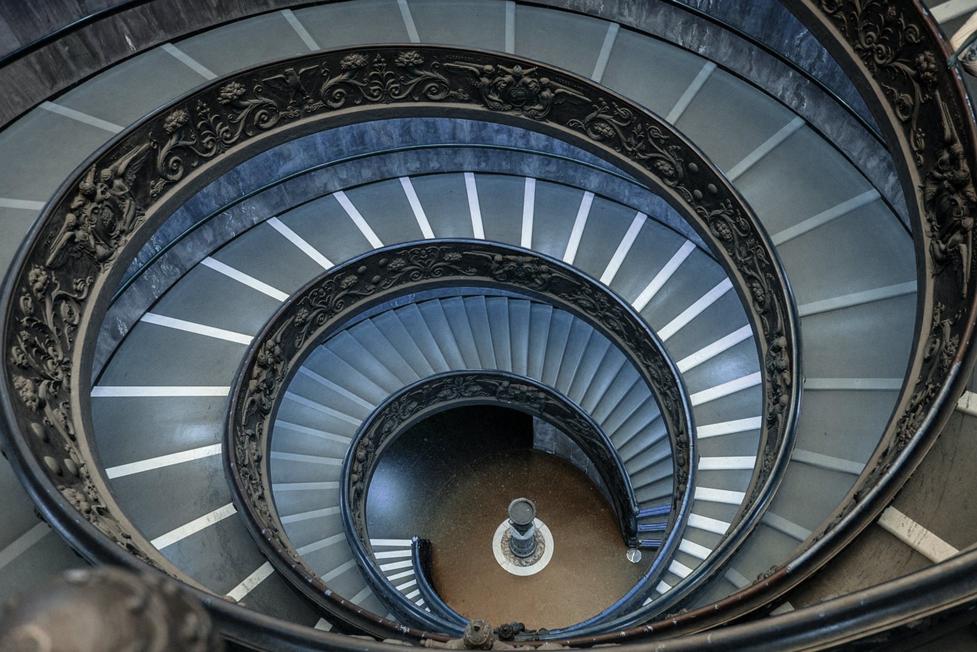 People walk down a spiral staircase in a museum.