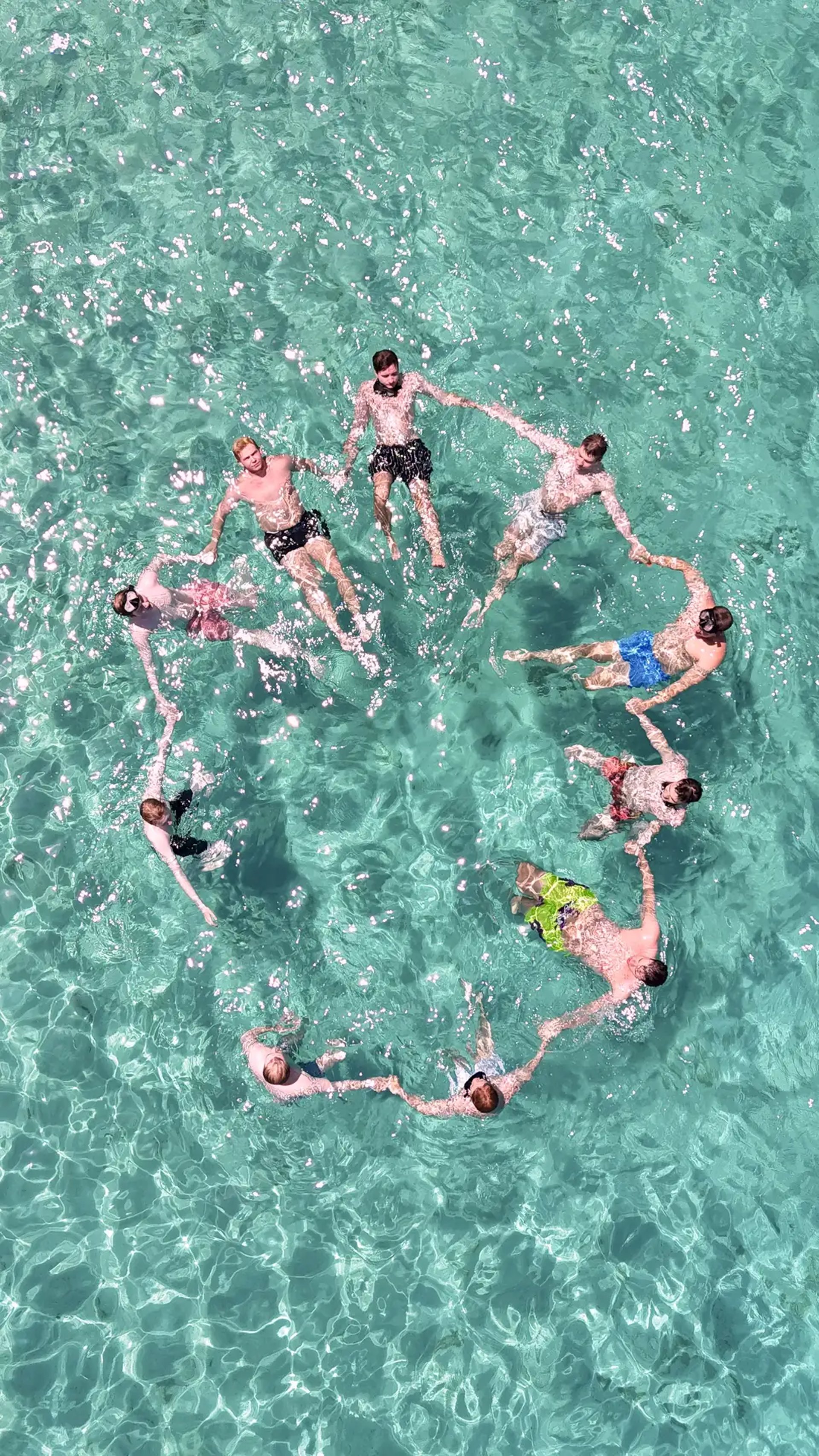 rone view of people forming a star while floating in crystal-clear waters of Drvenik Mali on a private boat tour from Split