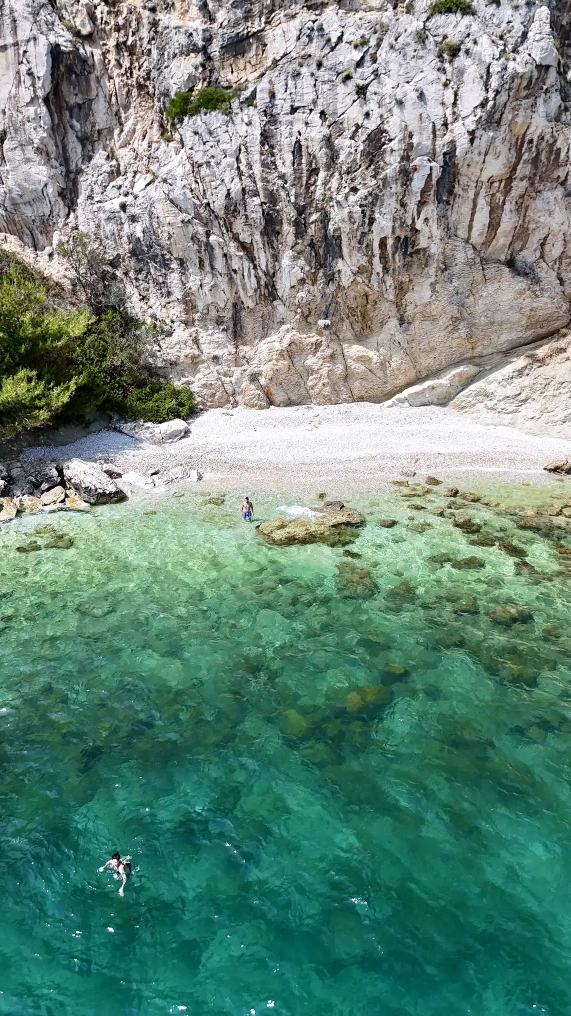 Aerial panoramic view of a hidden beach beneath dramatic cliffs on Ciovo during a private boat tour from Split, Croatia