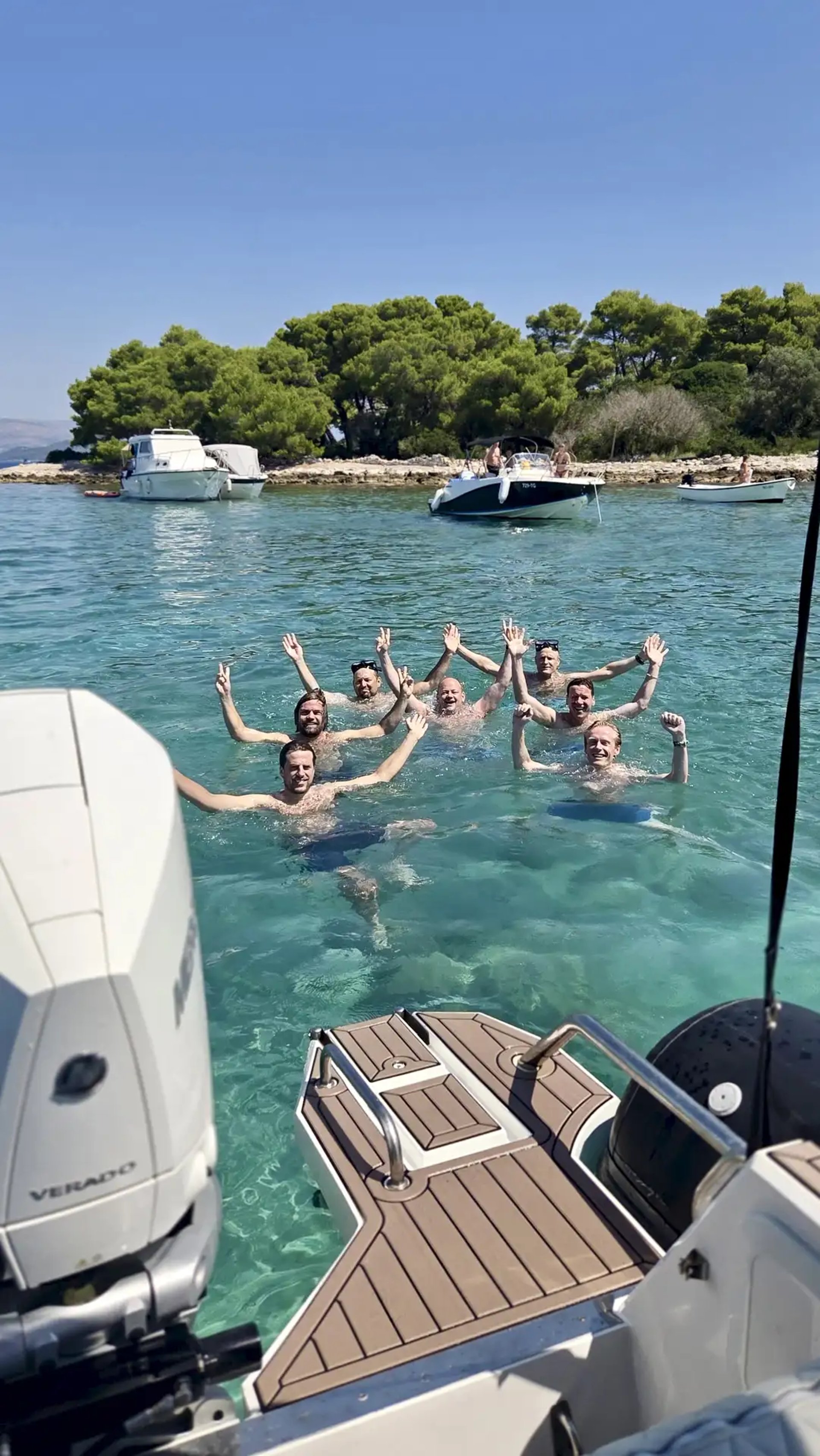 Guests celebrating and swimming in the Blue Lagoon with a Mercury outboard engine visible behind the boat