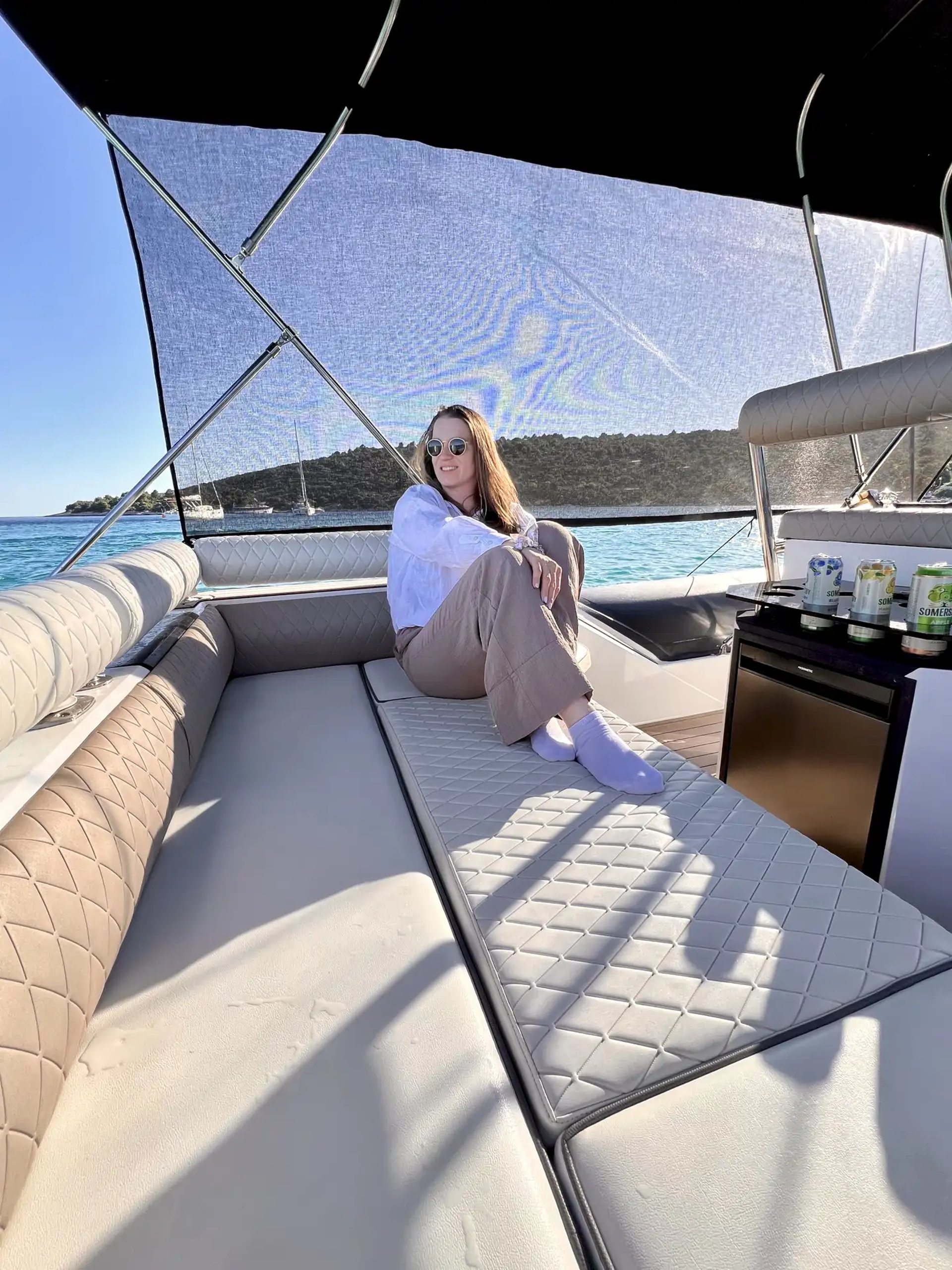 Guest on the rear sundeck of Hunter Pro 800 RIB with sunshade curtain, fridge & drinks during a private boat tour from Split.