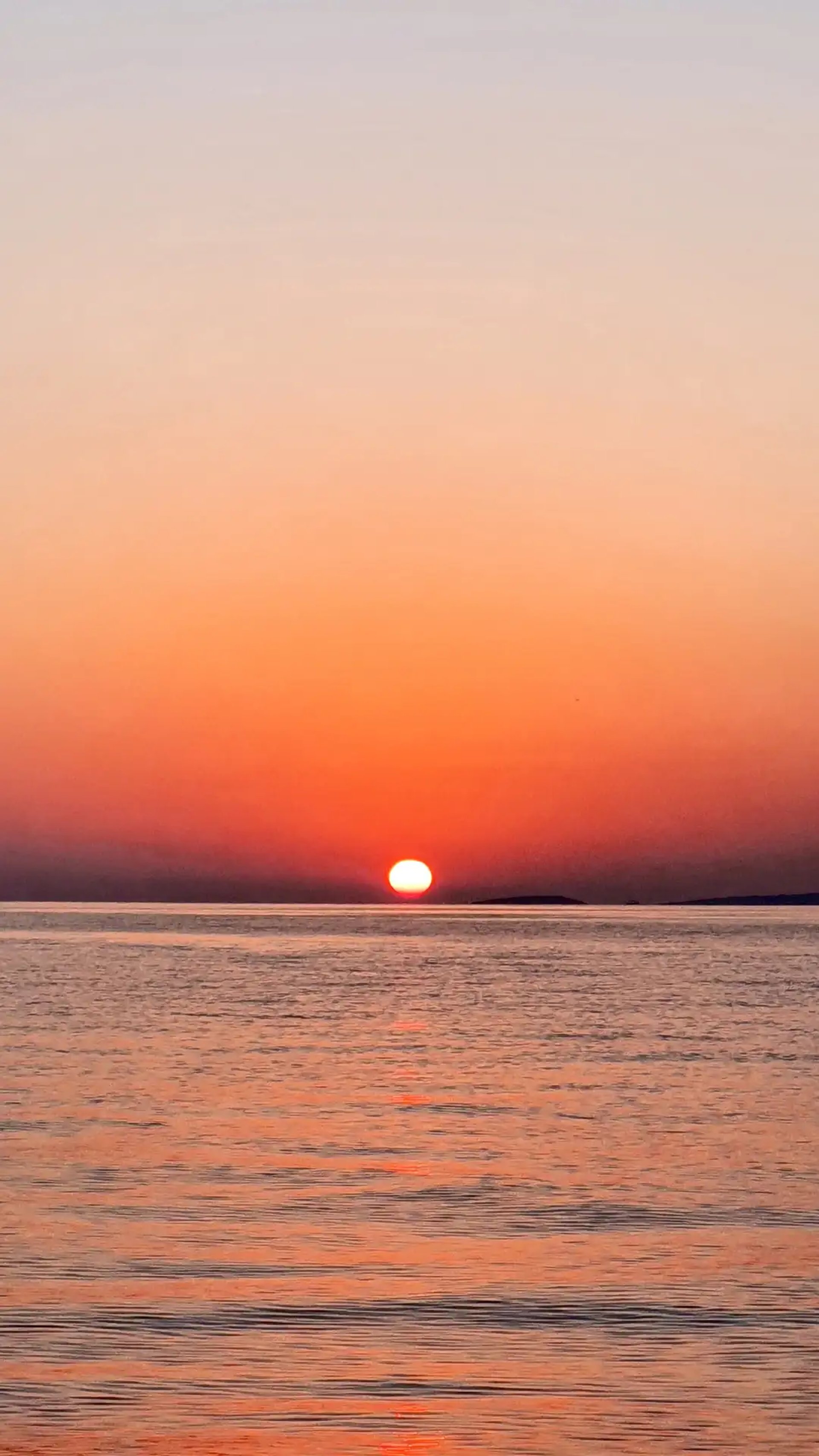 Calm romantic Adriatic sunset with island silhouettes and the sun about to dip into the sea photographed from a boat