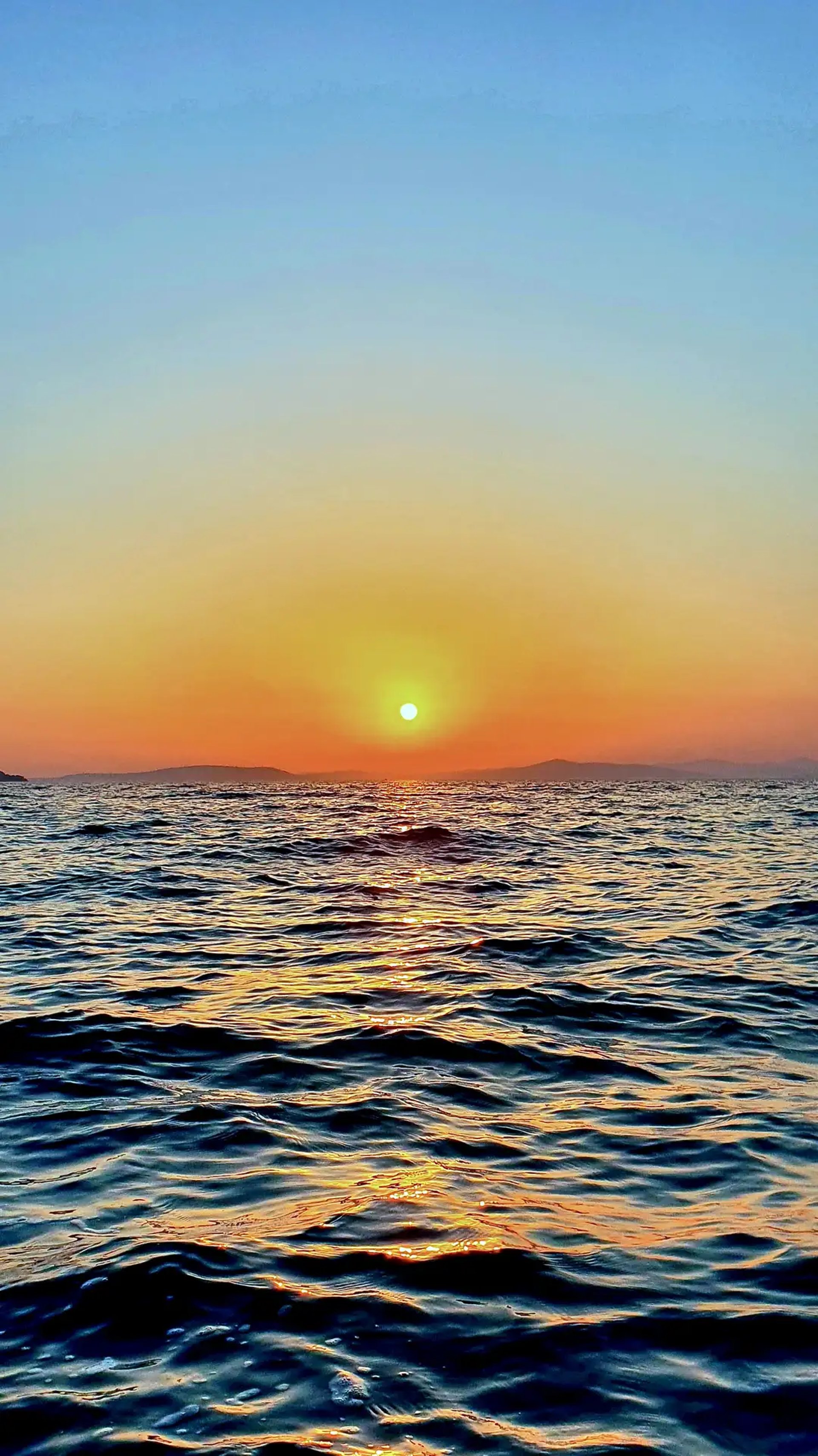 Dramatic Adriatic sunset with island silhouettes and the sun about to dip into the sea photographed from a boat
