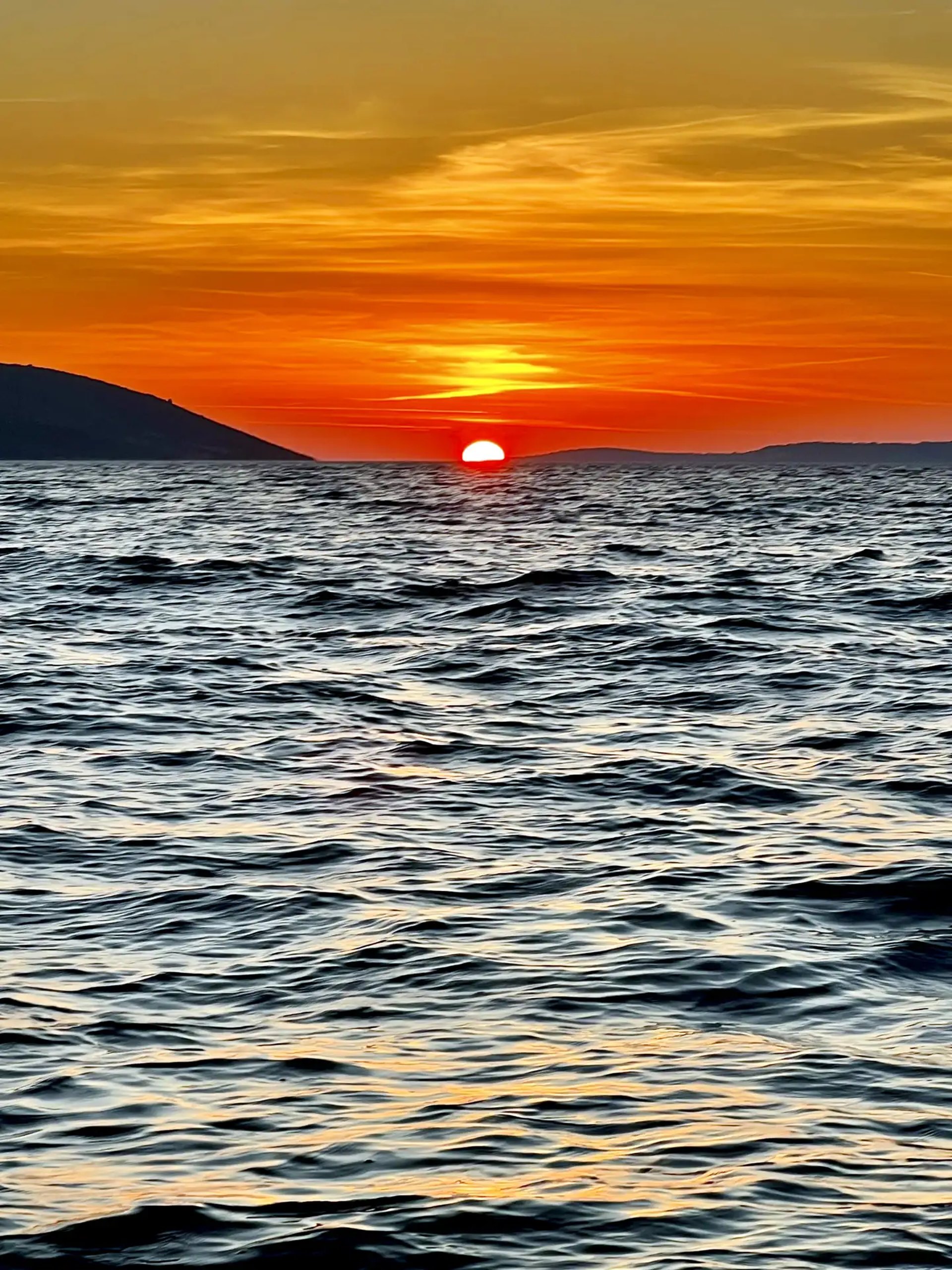 Dramatic Adriatic sunset with island silhouettes and the sun about to dip into the sea photographed from a boat