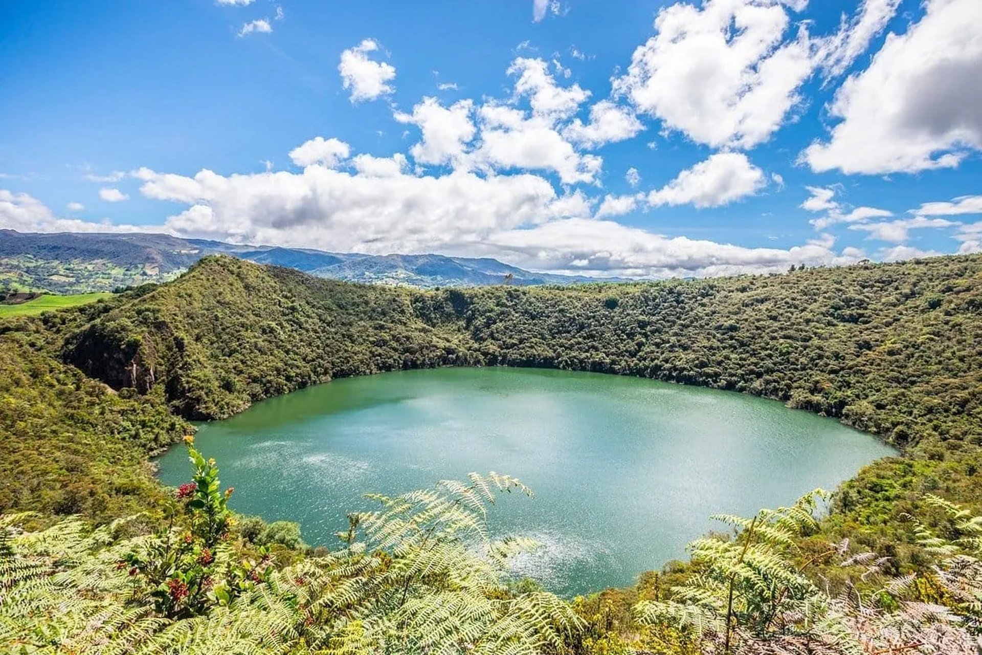 Wide panoramic view of the emerald-green Guatavita Lagoon header image for a private luxury tour.