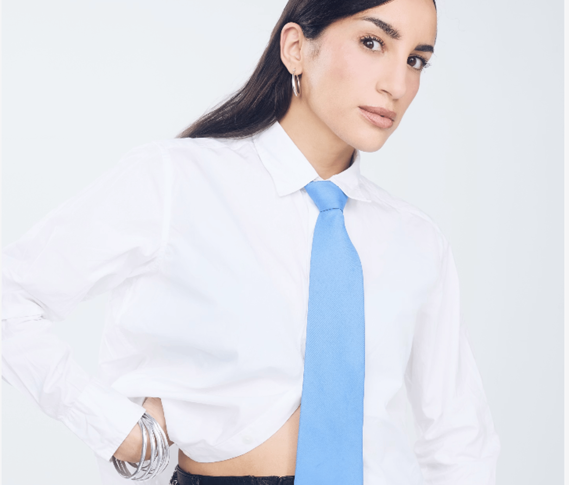 Woman in white shirt and blue tie with jewelry