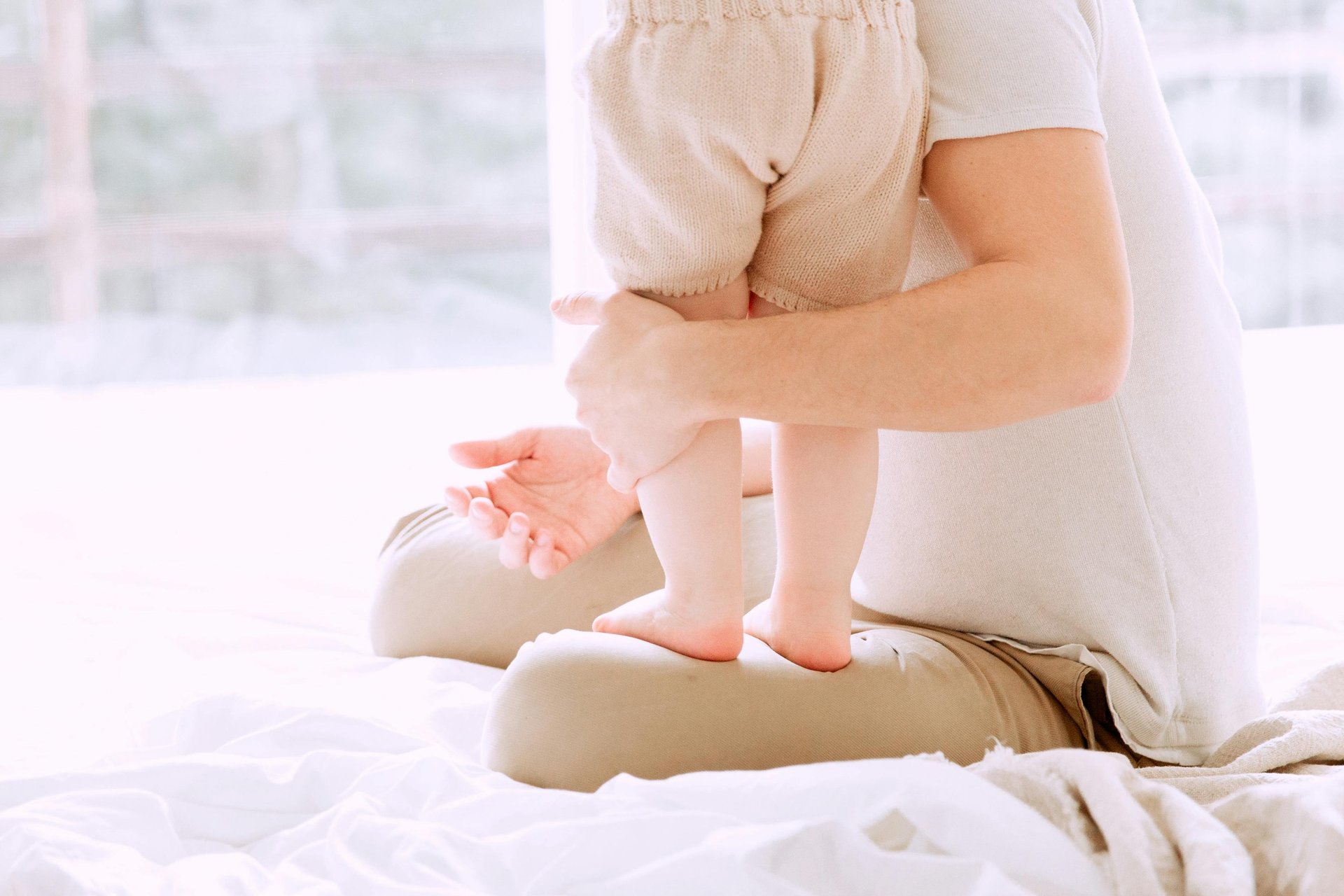 Toddler standing on father's legs while he sits