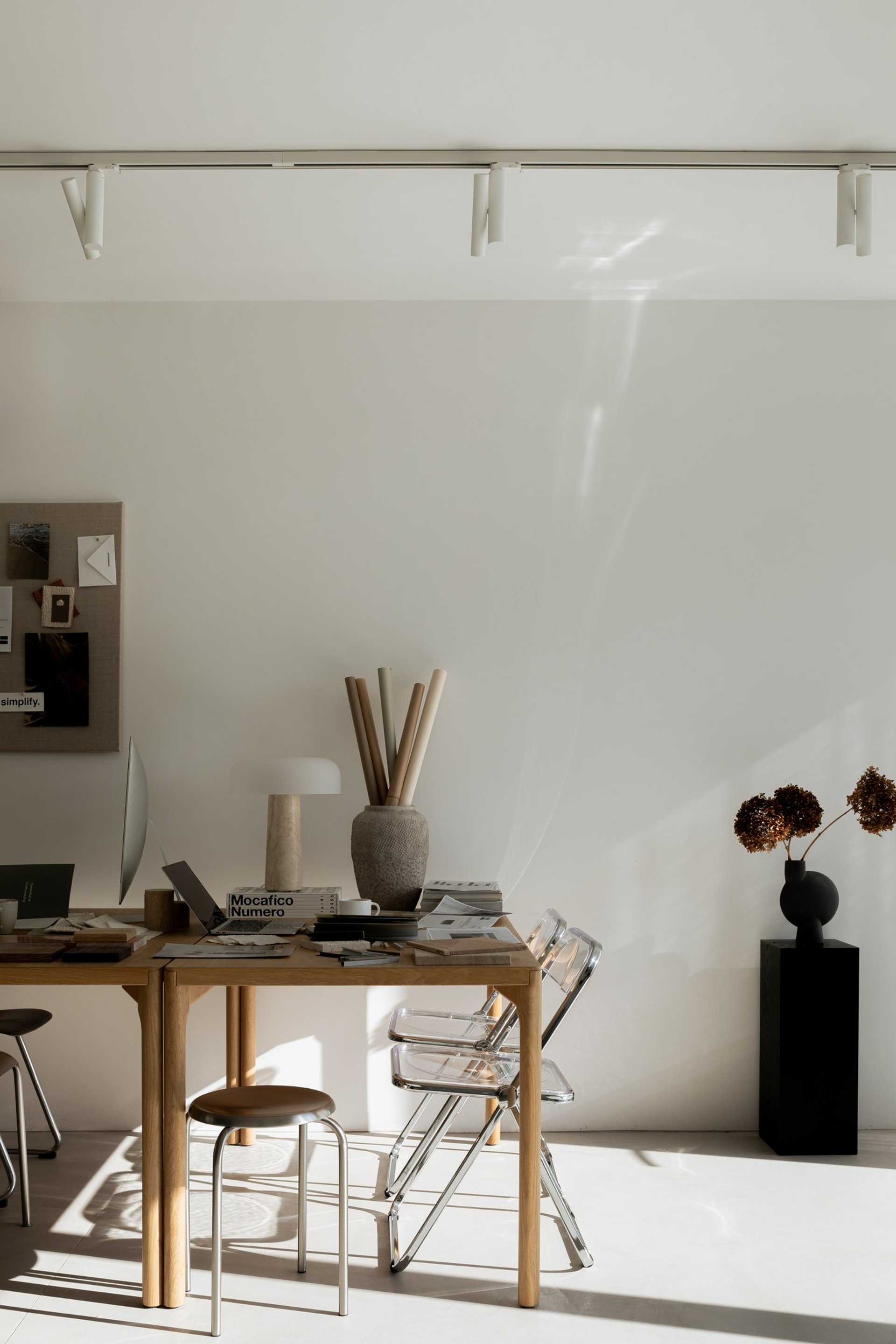 Minimalist arrangement of two blooming white tulips in a textured ceramic vase against a tan background.