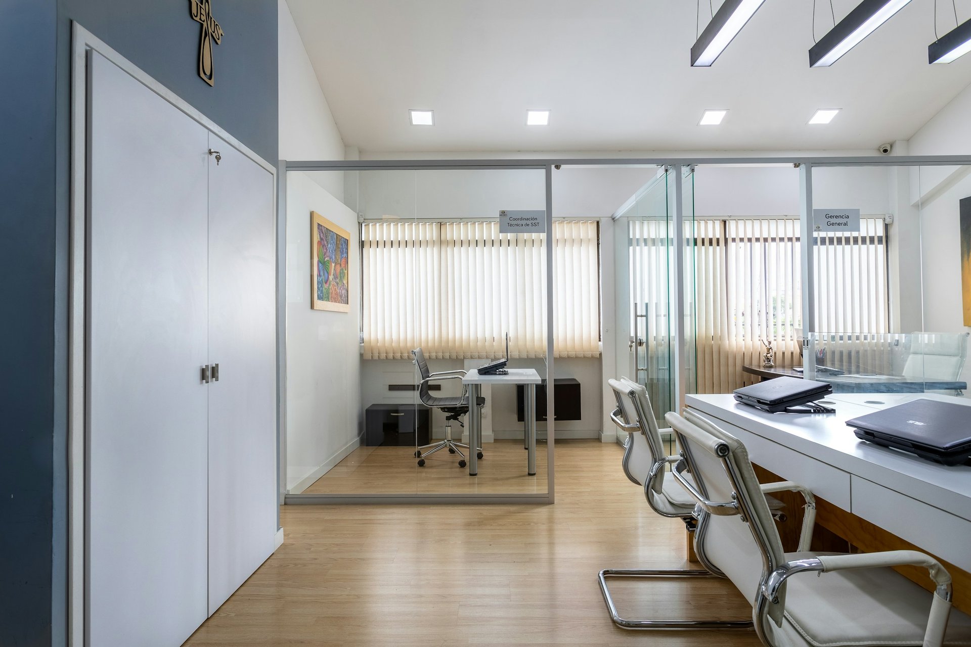 Modern white office interier with hardwood floors and white desks with black laptop computers.