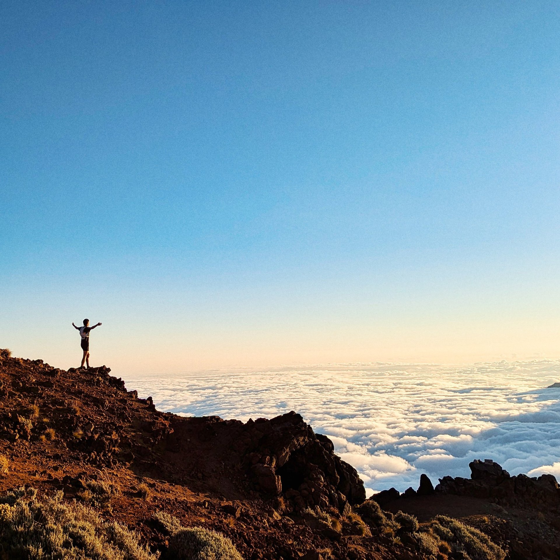 silhouette of man jumping on rocky mountain during sunset
