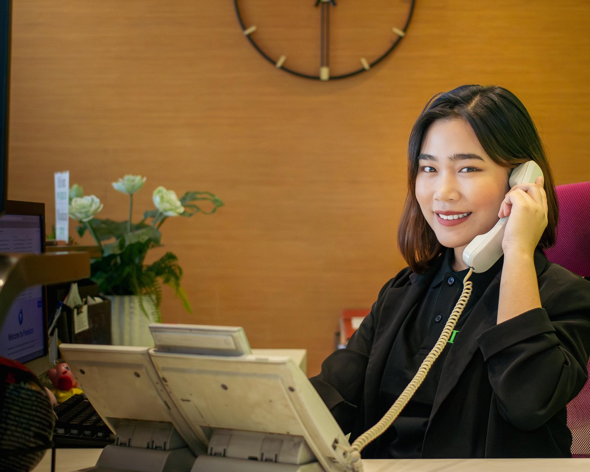 A smiling woman wearing a headset at a computer.