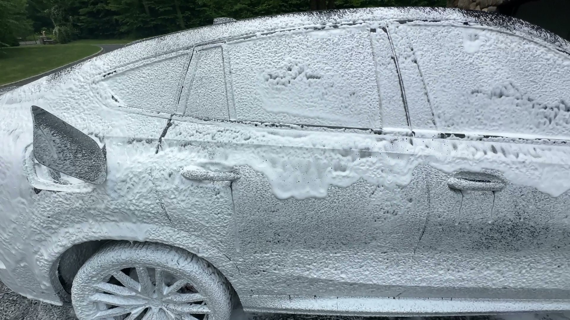 car detailing showcasing foam cannon on black suv covered in soap