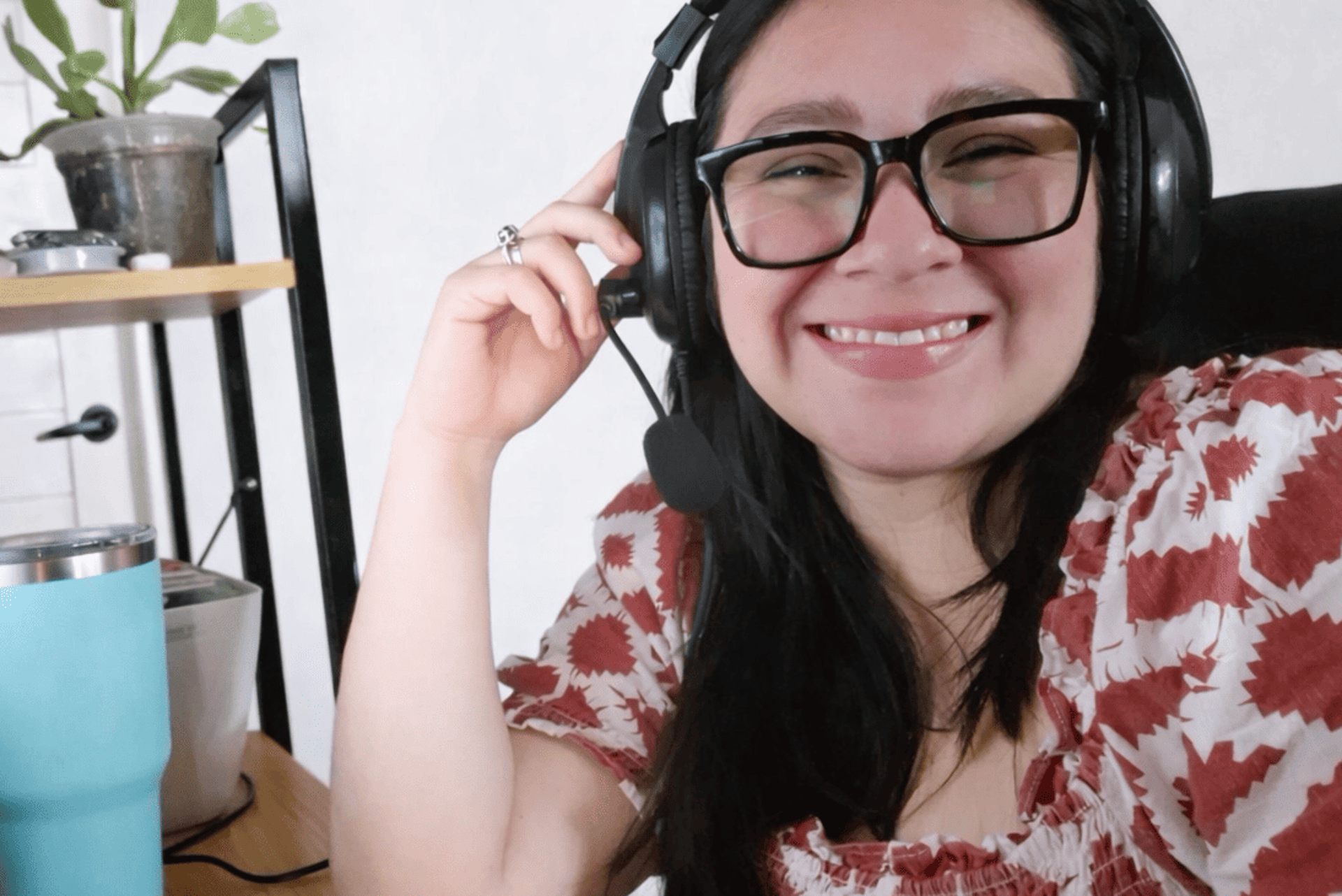 Teacher in her office smiling at the camera while wearing headphones
