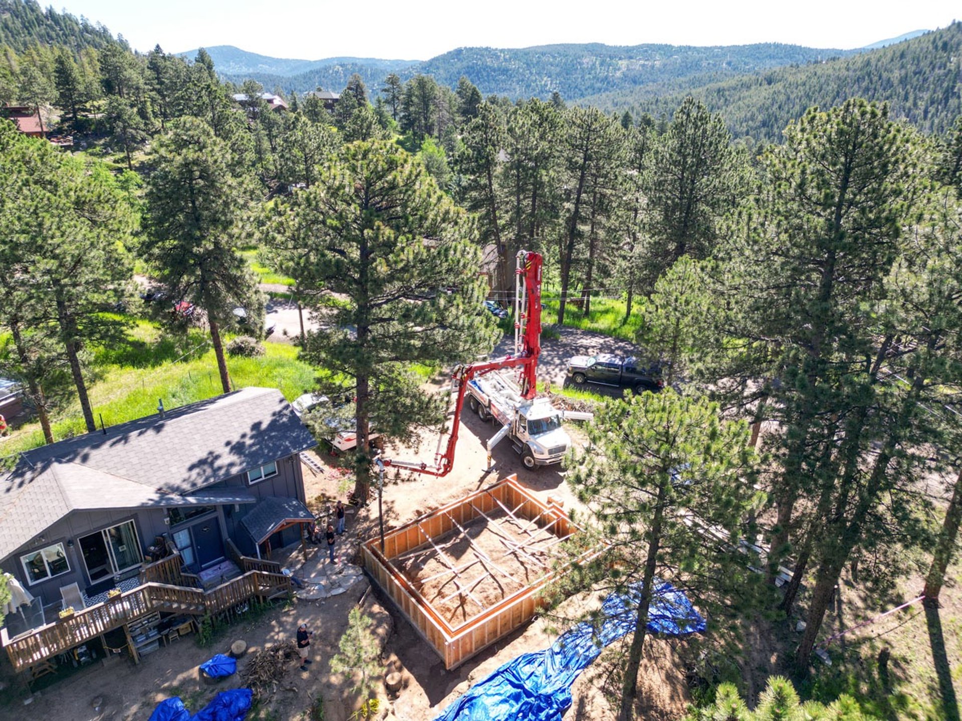 Aerial shot of concrete pump truck and crew at a mountain job site.