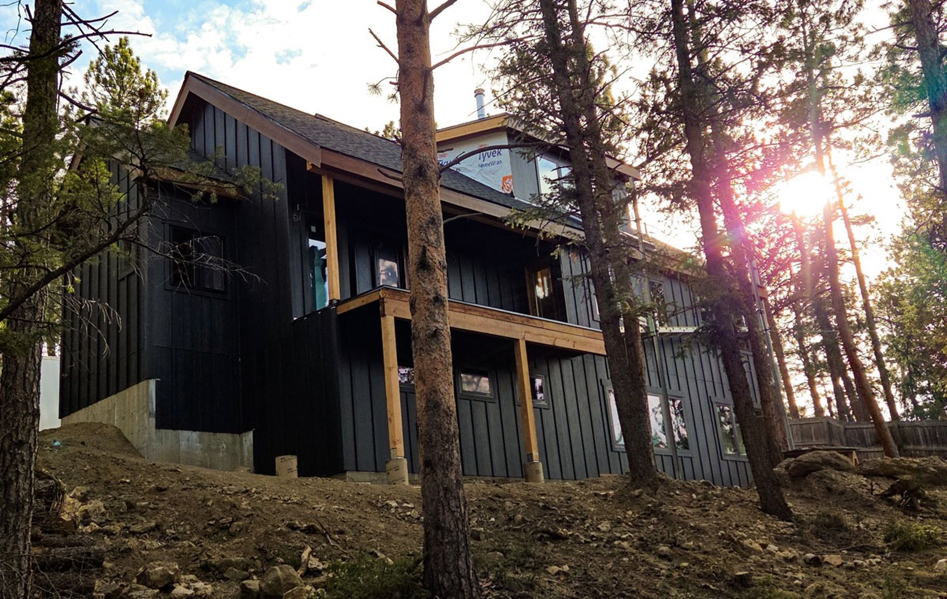 Finished rear exterior of a custom mountain home with elevated deck and dark metal siding.