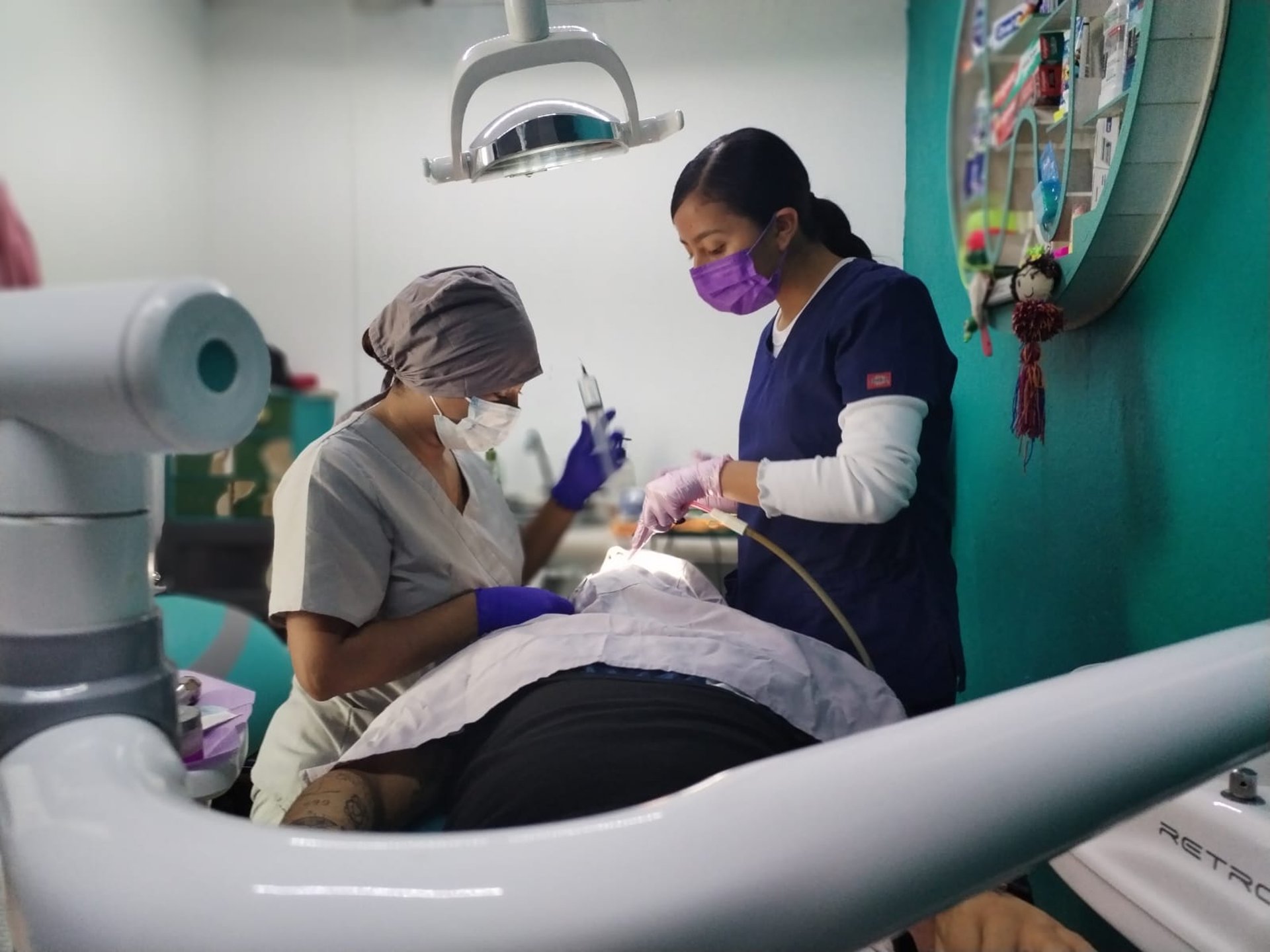 Dentista profesional y asistente dental realizando una limpieza a un paciente en una clinica dental