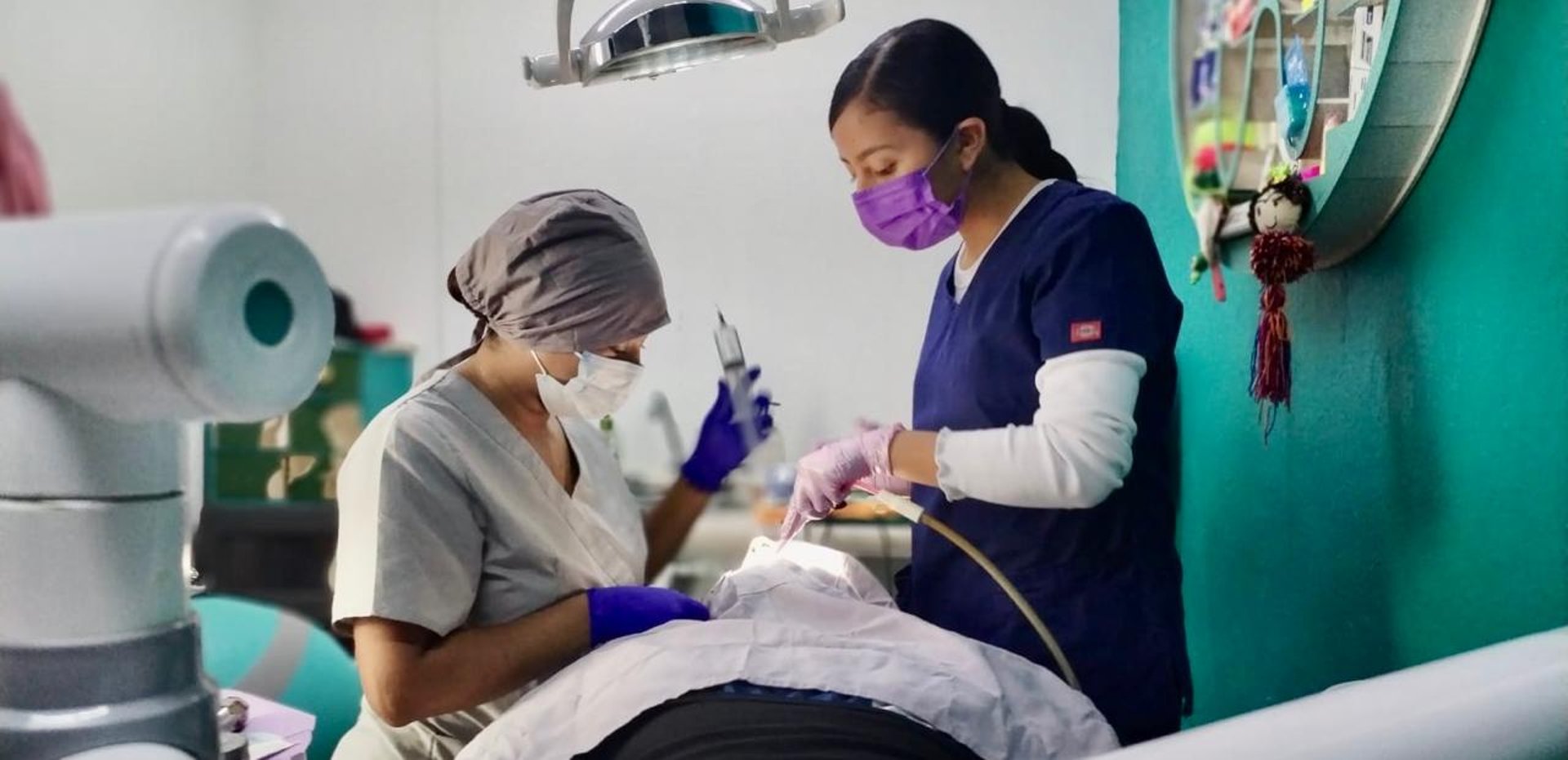 Dos dentistas con herramientas de limpieza dental atendiendo a un paciente