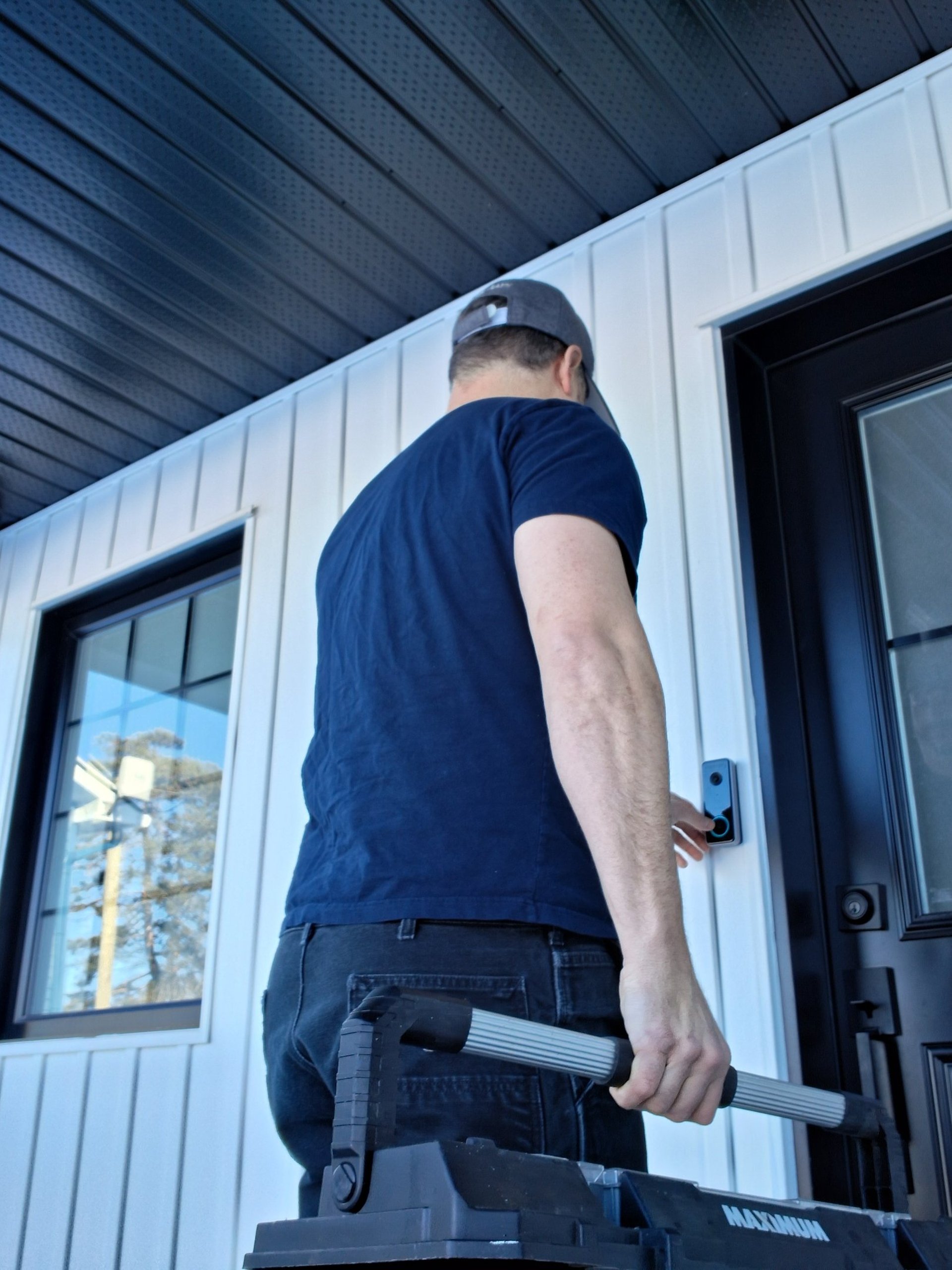 Technician at residential front door installing a smart video doorbell.