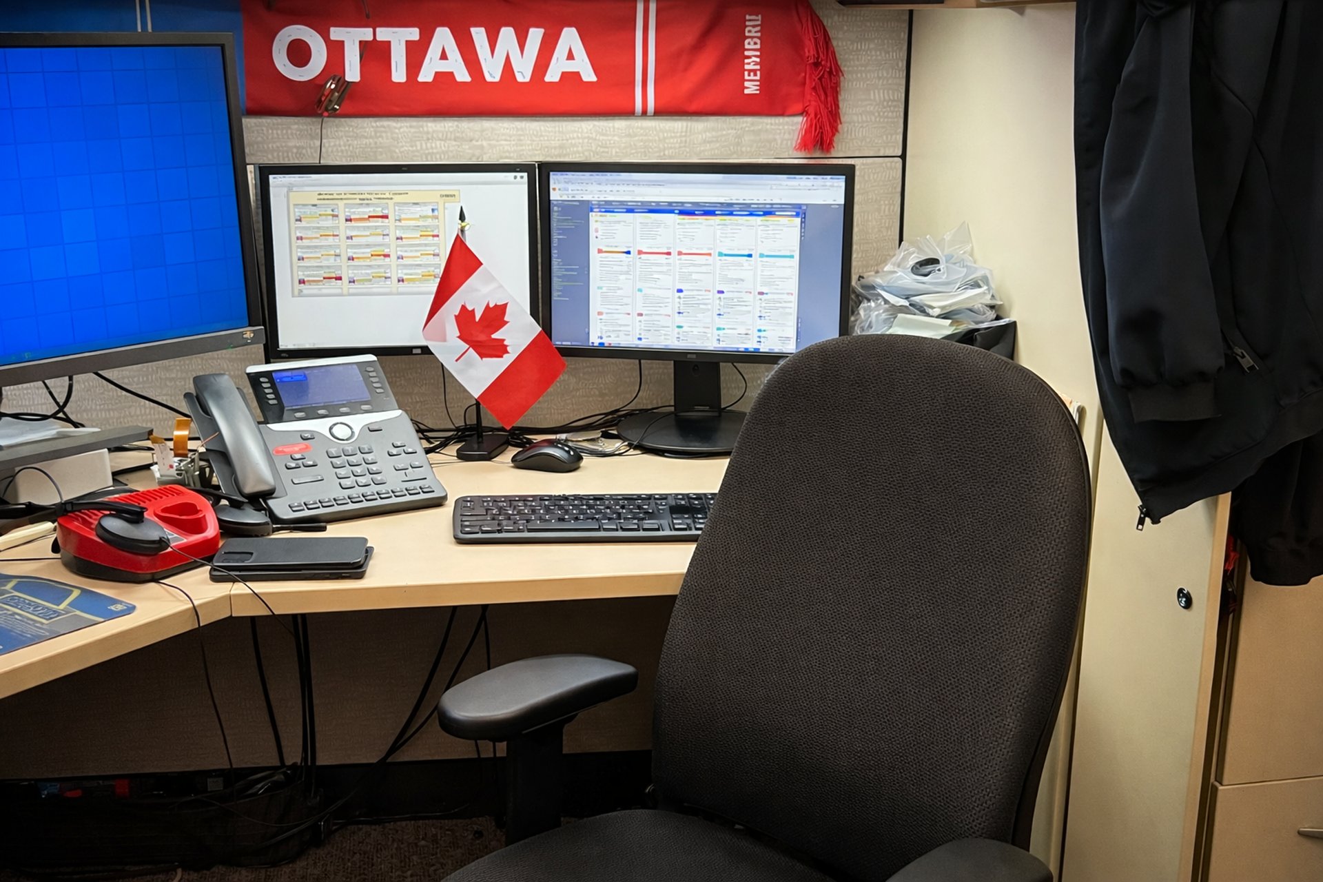 Office workstation with dual monitors, desk phone, and Canadian flag under Ottawa banner.