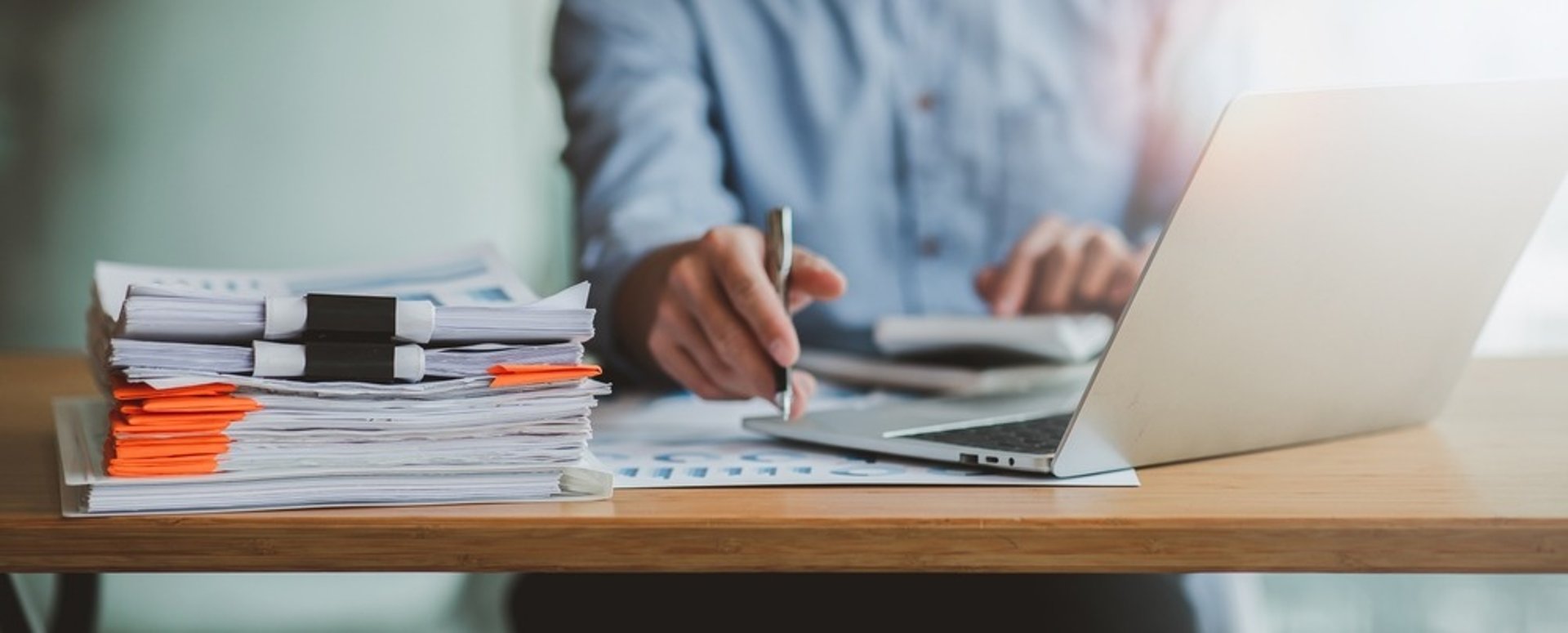 person holding pencil near laptop computer