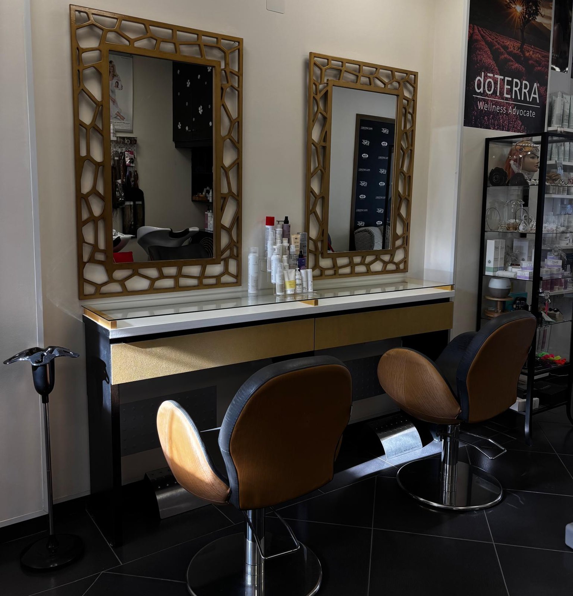 grayscale photo of woman using laptop near three salon chairs