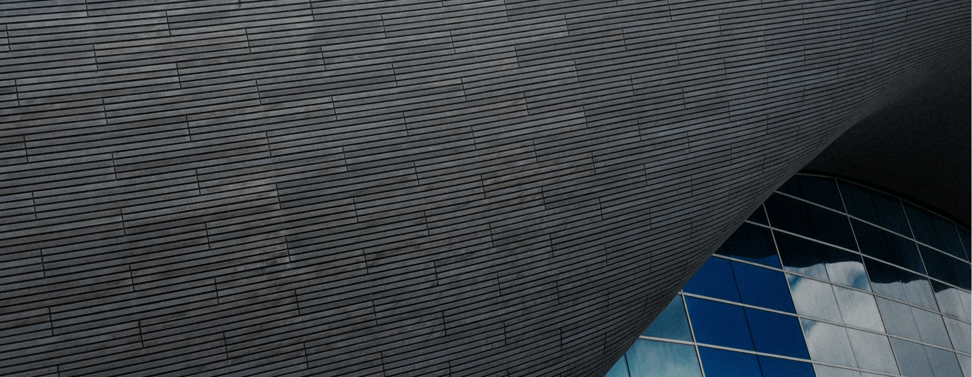 an abstract photo of a curved building with a blue sky in the background