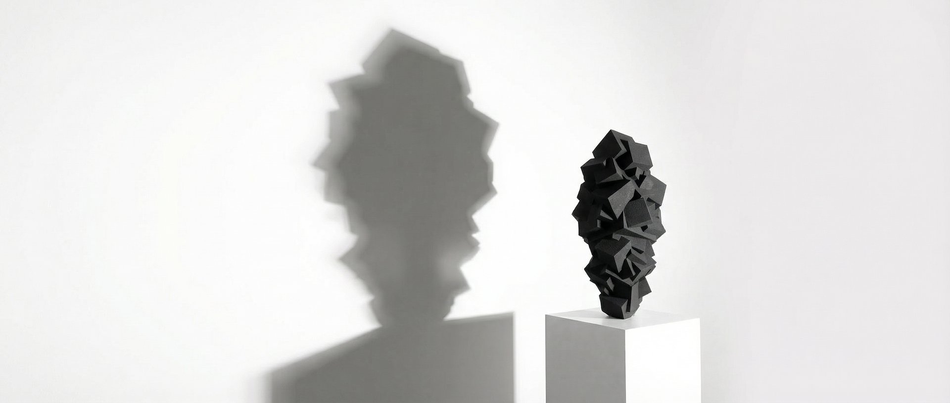 Sculpture Pyrite noire monochrome sur socle blanc, ombre portée sur mur