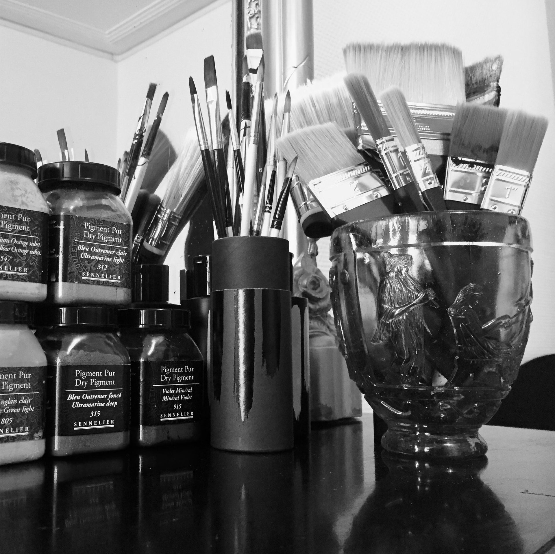Détail atelier Stanislas Garaud, pinceaux, brosses, pots de pigments purs Sennelier sur cheminée marbre noir
