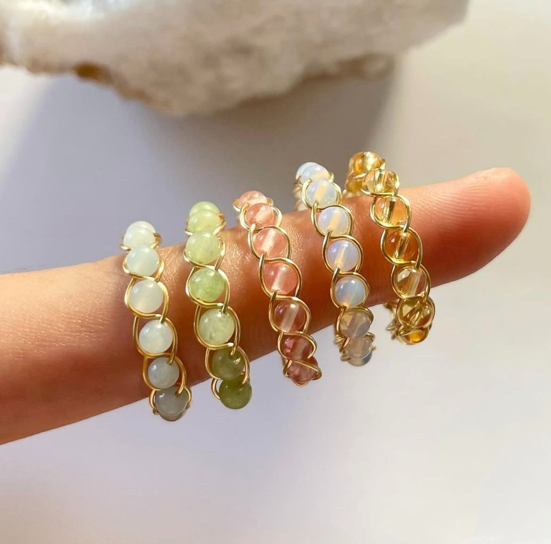 Anillos de alambre dorados con cuentas de diferentes colores en un dedo.