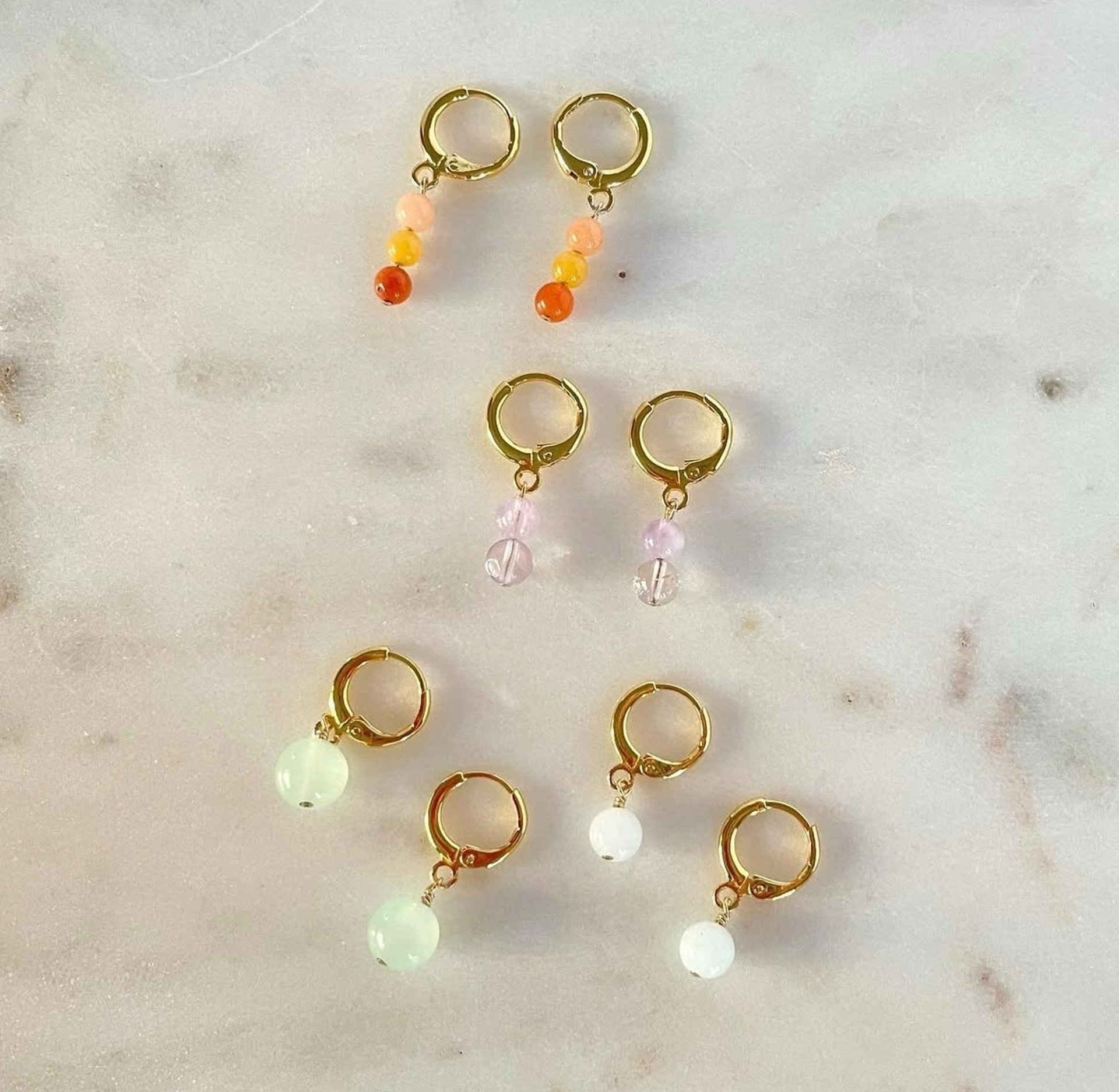 Aros dorados de diferentes tipo de color de cuentas sobre una superficie marmoleada.