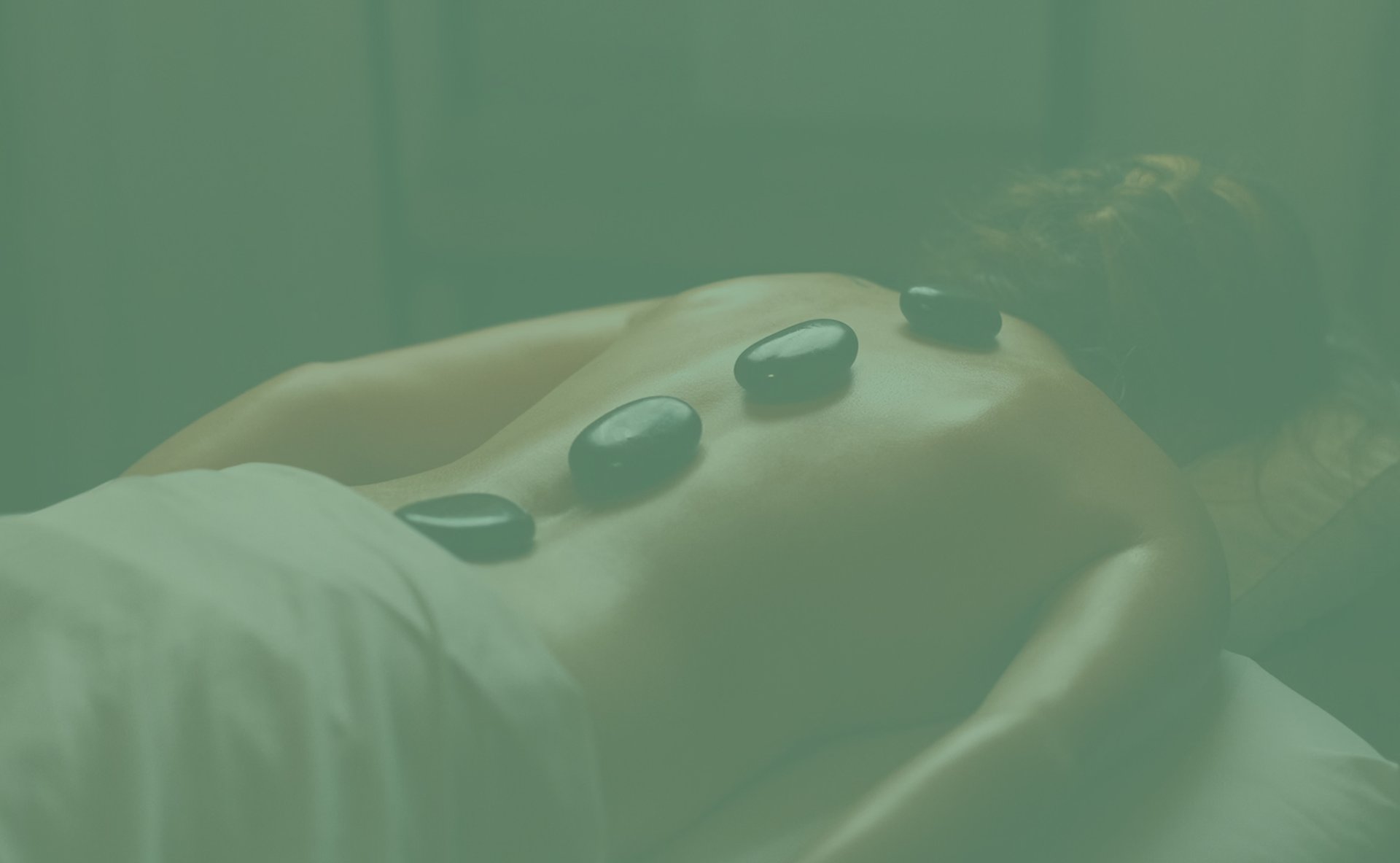 a woman laying on a bed with hot stones on her back