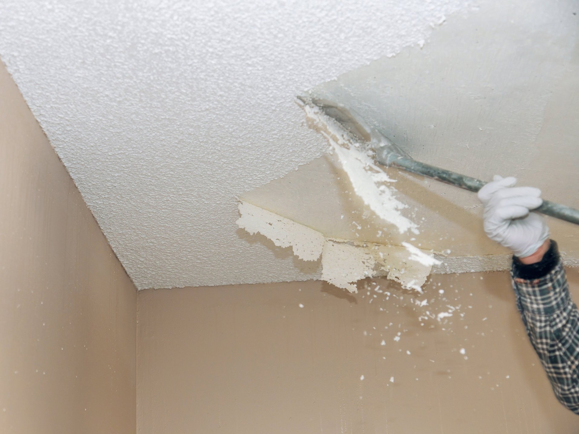 Hands applying plaster to a wall with trowels