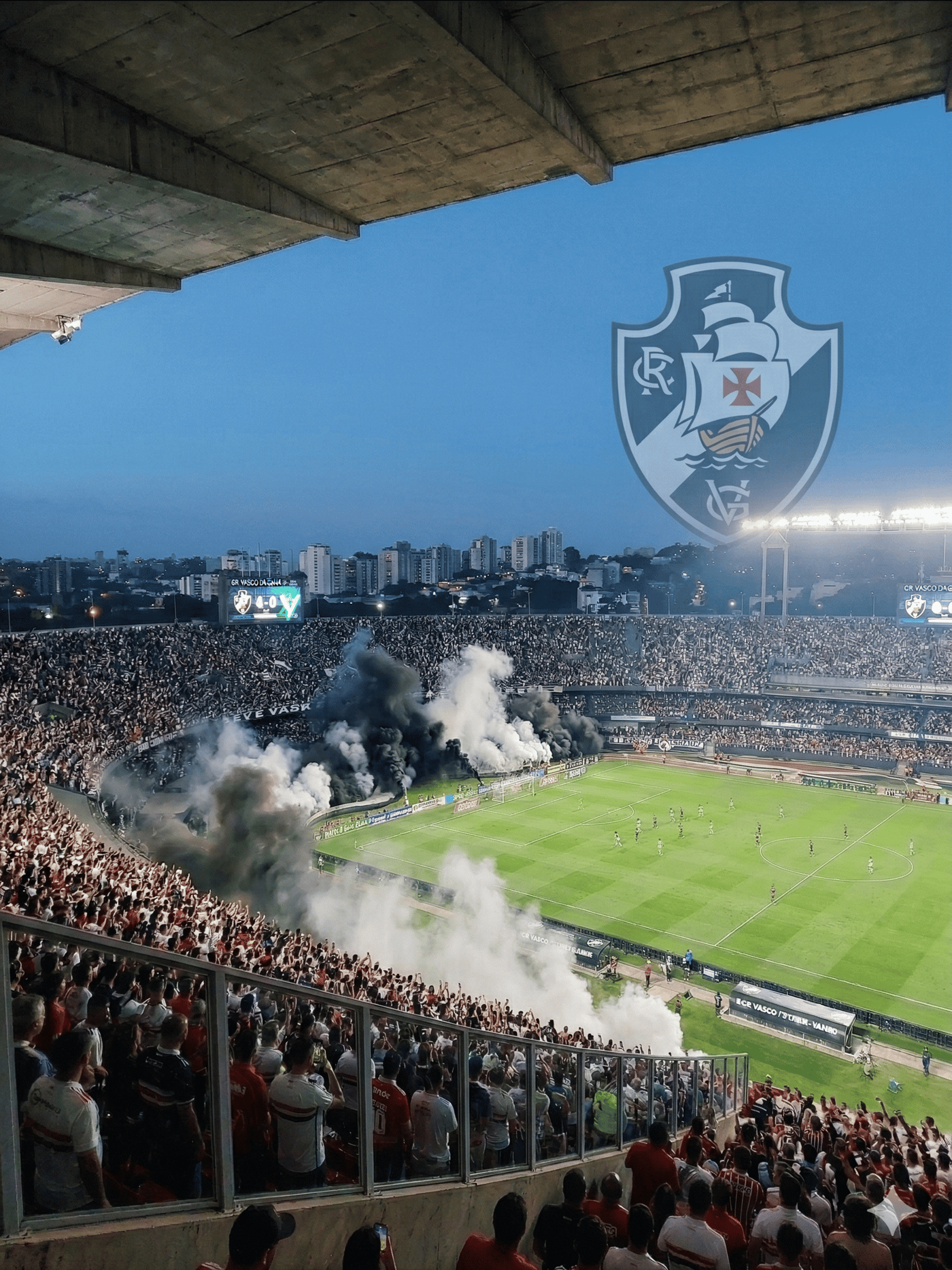 Vista panorâmica imponente de São Januário lotado com a Torcida Vascaína vibrando em noite de jogo.