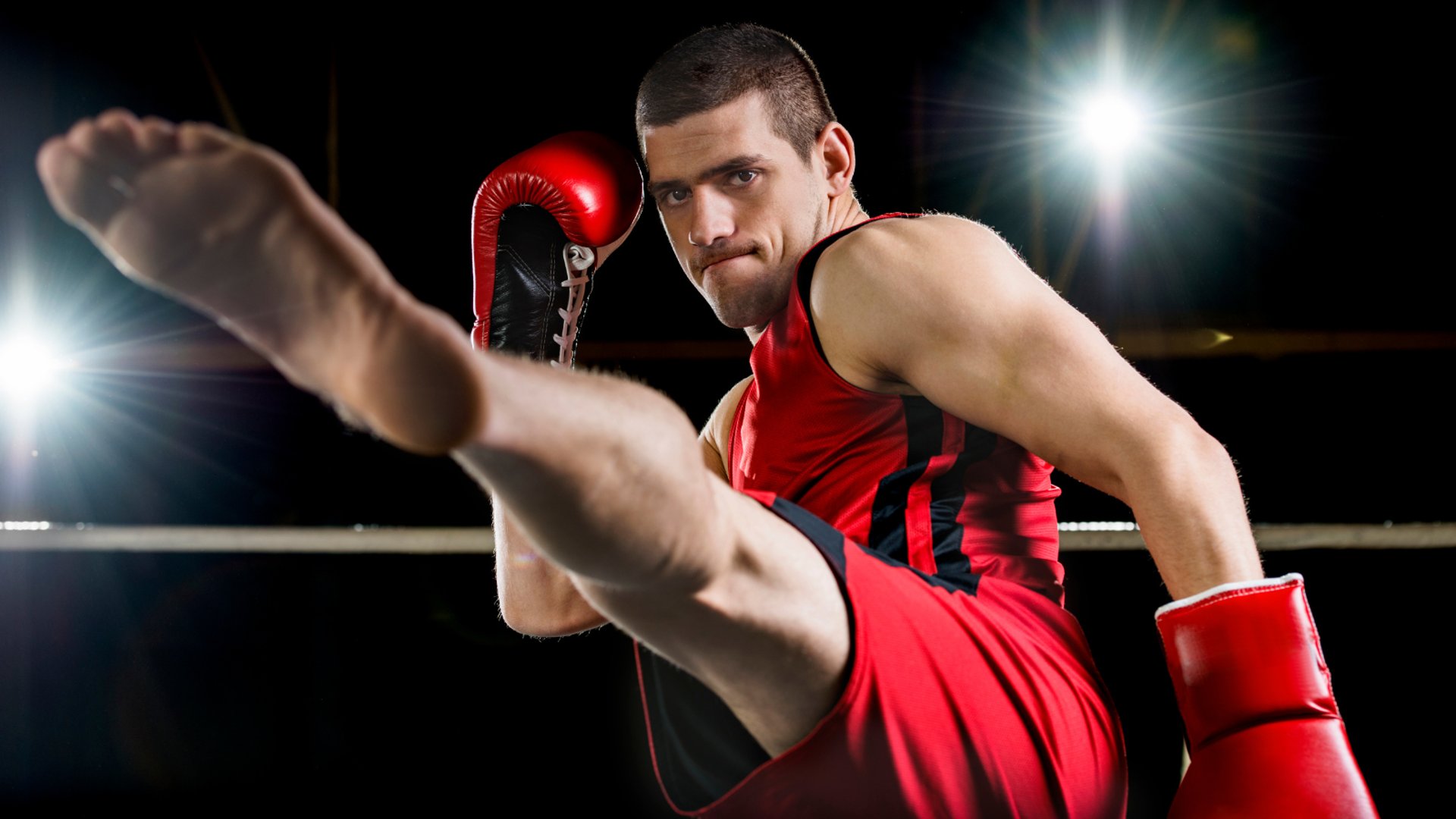 grayscale photo of people watching boxing with man wearing white bottoms inside boxing ring
