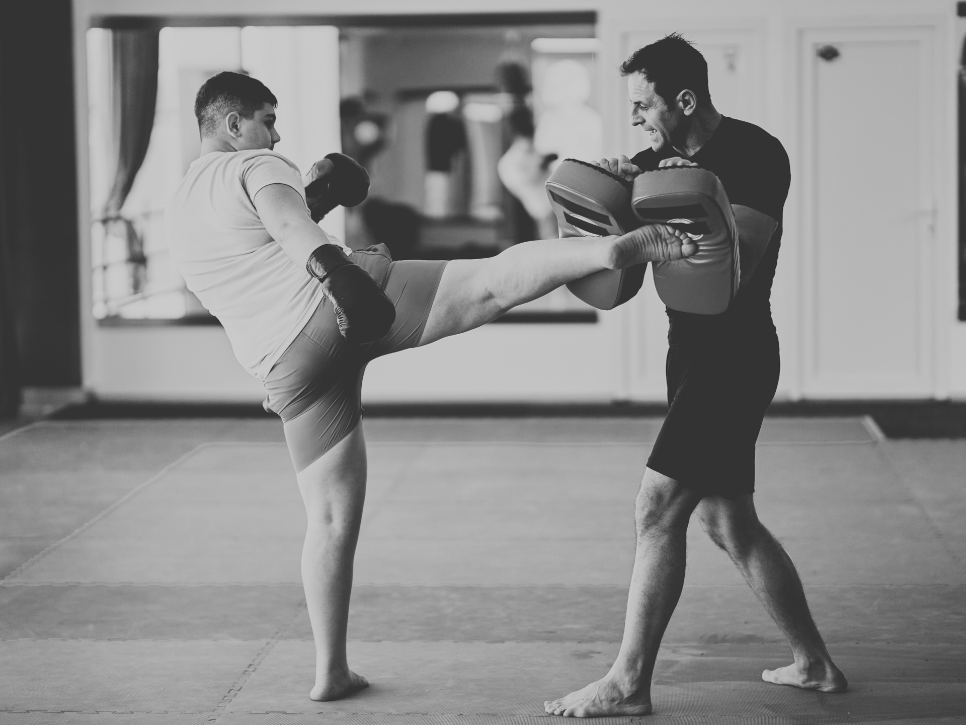 grayscale photo of people watching boxing with man wearing white bottoms inside boxing ring