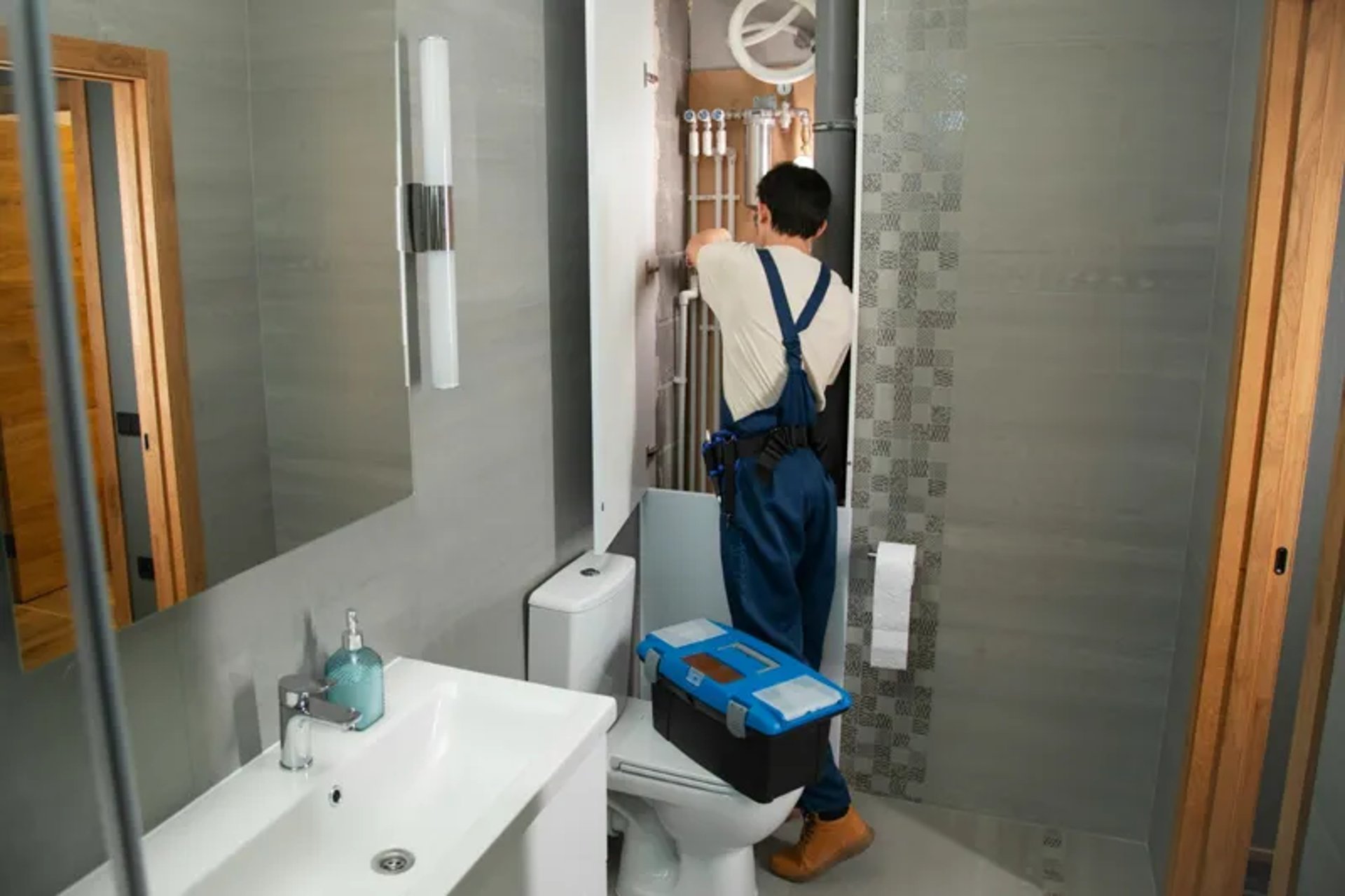 A plumber repairs plumbing in a bathroom.