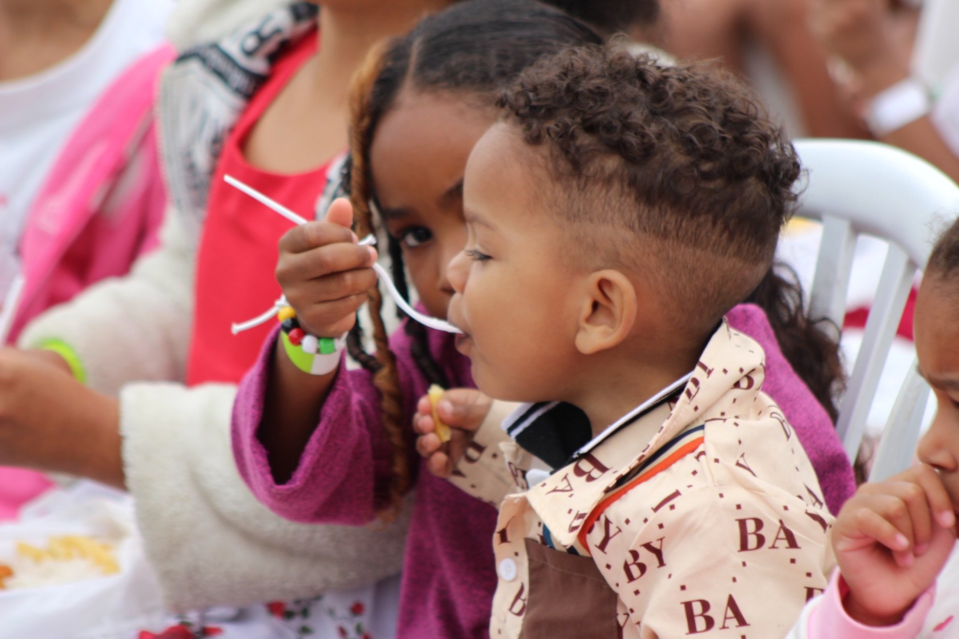 girl in pink tank top standing beside girl in blue and red dress
