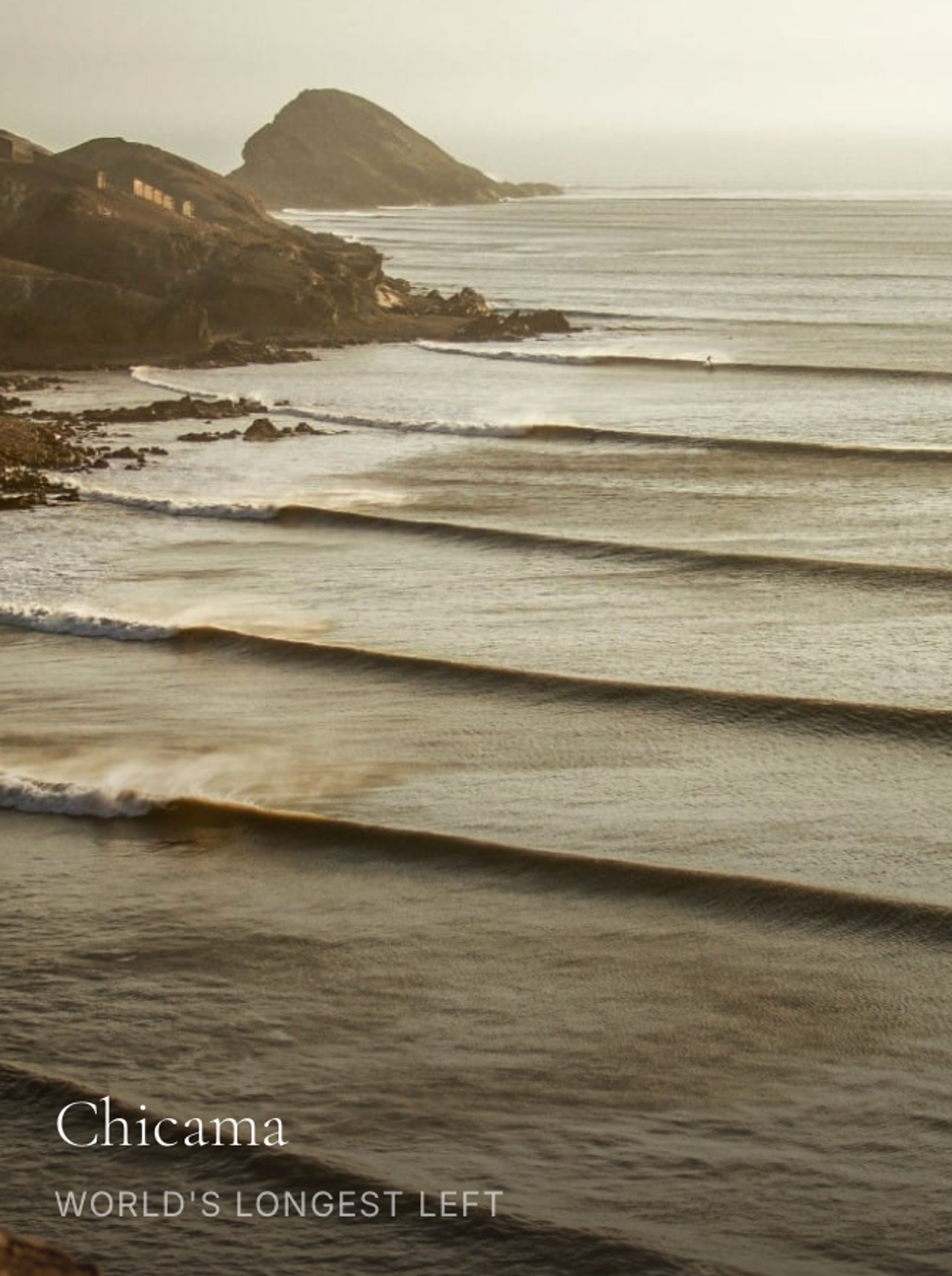 man sitting on sand beside surfboard facing sea during daytime