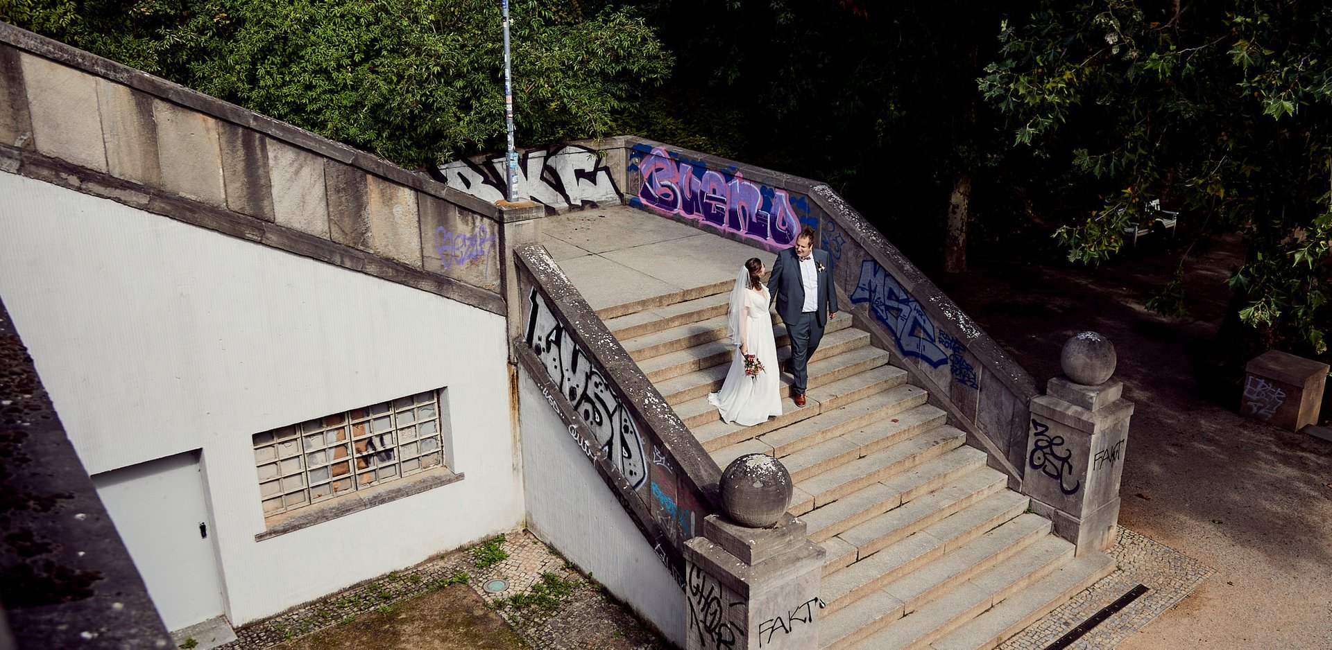 Bride and groom walking down the stairs in a park.
