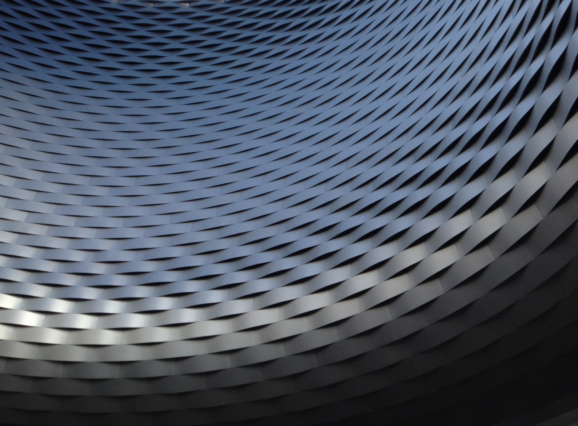 an abstract photo of a curved building with a blue sky in the background