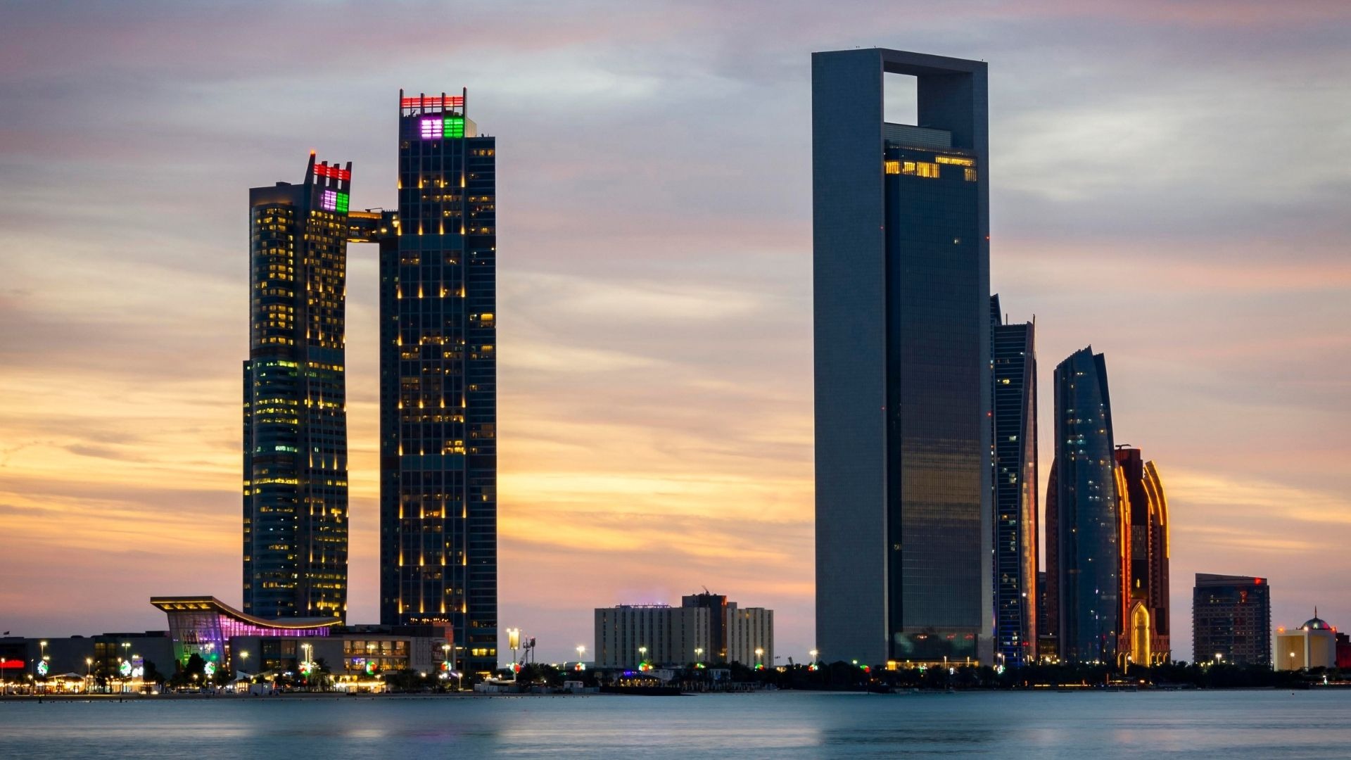 "Abu Dhabi skyline sunset with modern skyscrapers and city lights UAE waterfront"