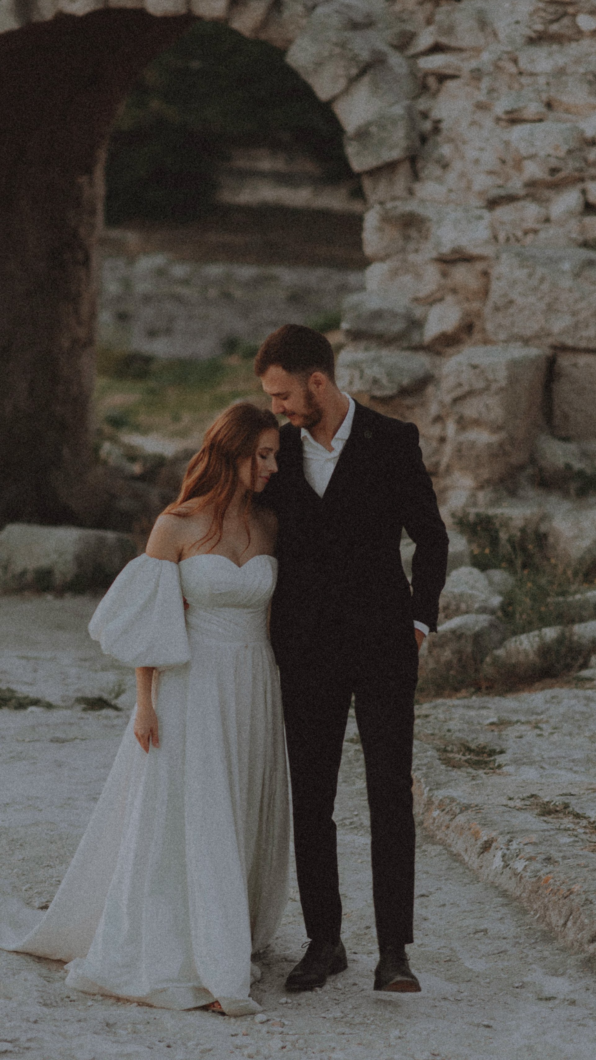 a bride and groom kissing on the beach