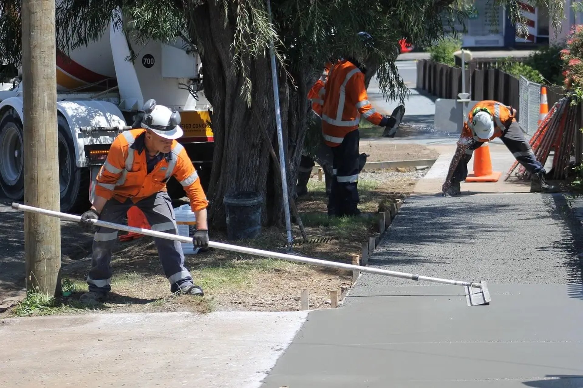 Men wearing construction safety vest while working on concrete sidewalks