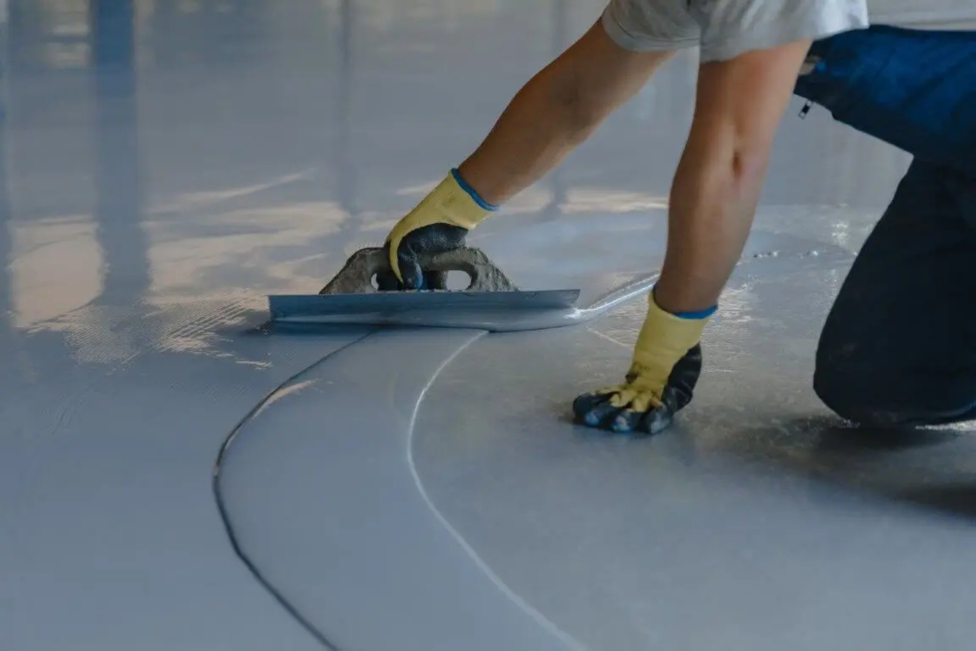 Man is applying a gray epoxy finish on a concrete surface