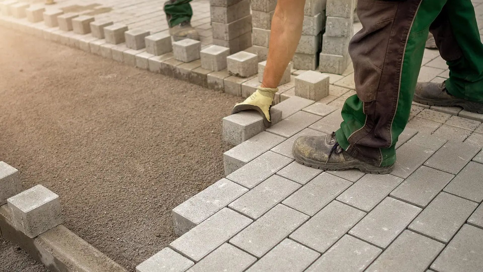 men laying a concrete blocks for paving sidewalk