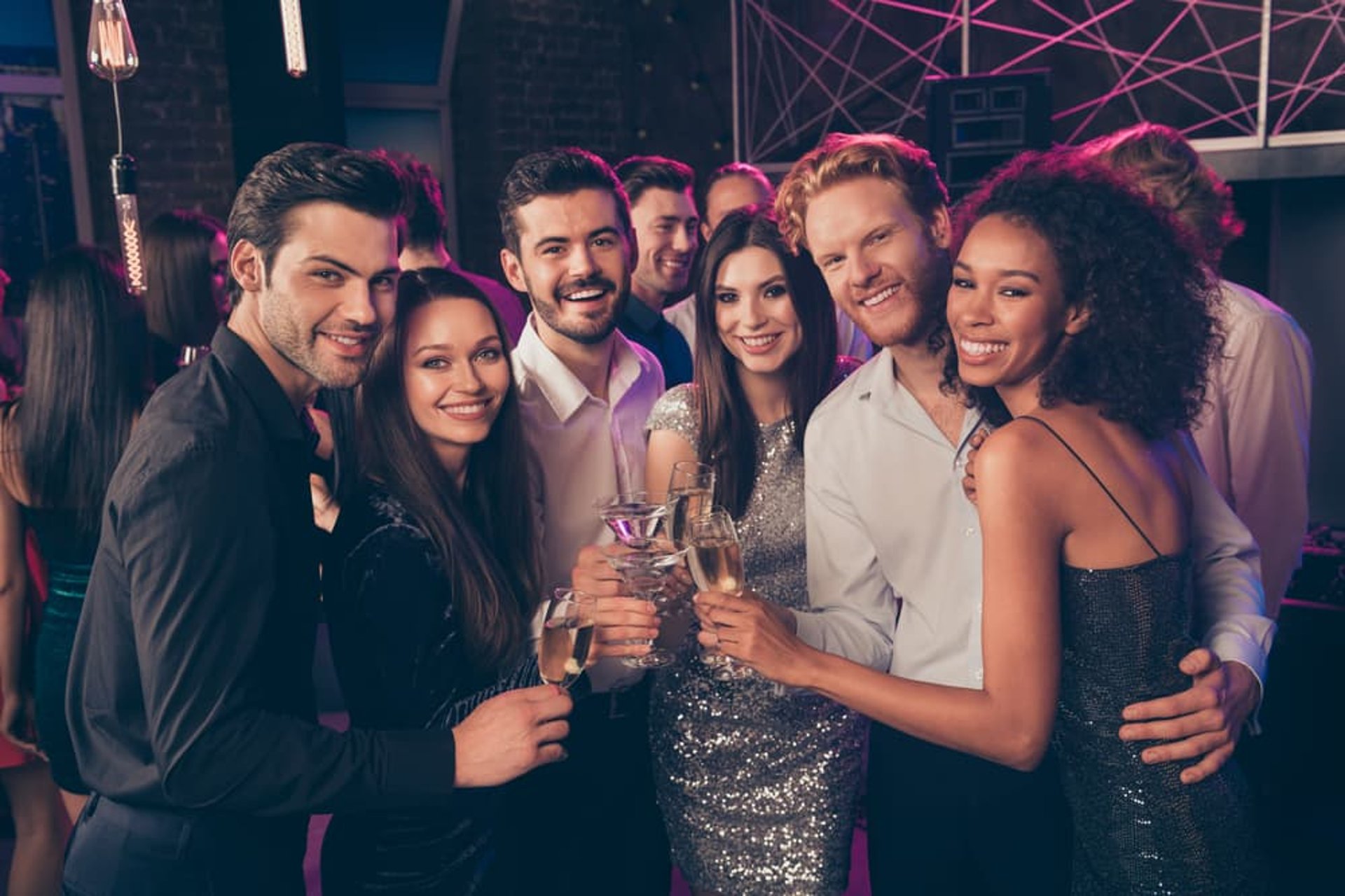 Group of friends celebrating with drinks at a vibrant Downtown Las Vegas nightlife venue during a club crawl.