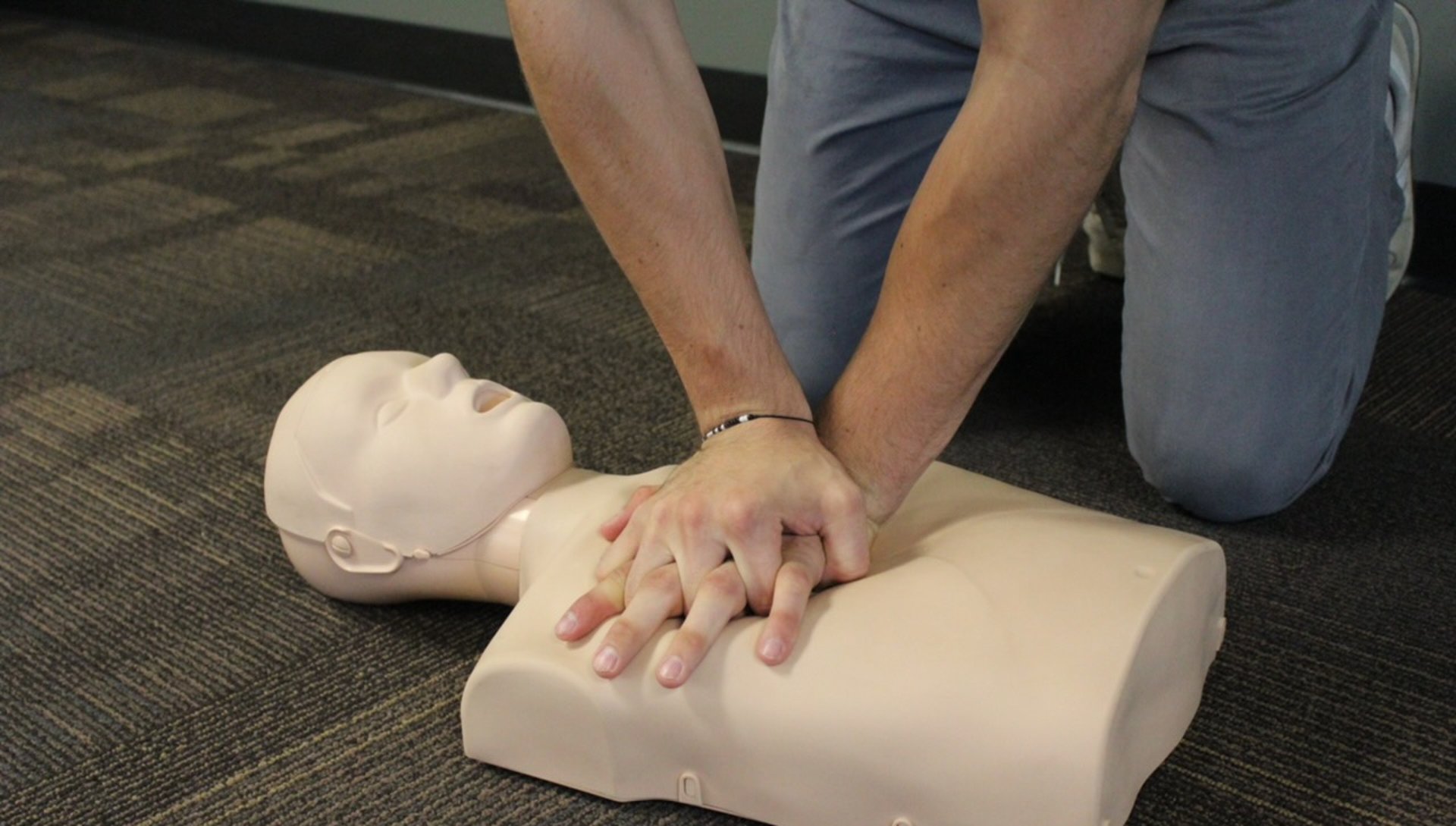 man in gray long sleeve shirt and black pants sitting on brown wooden floor