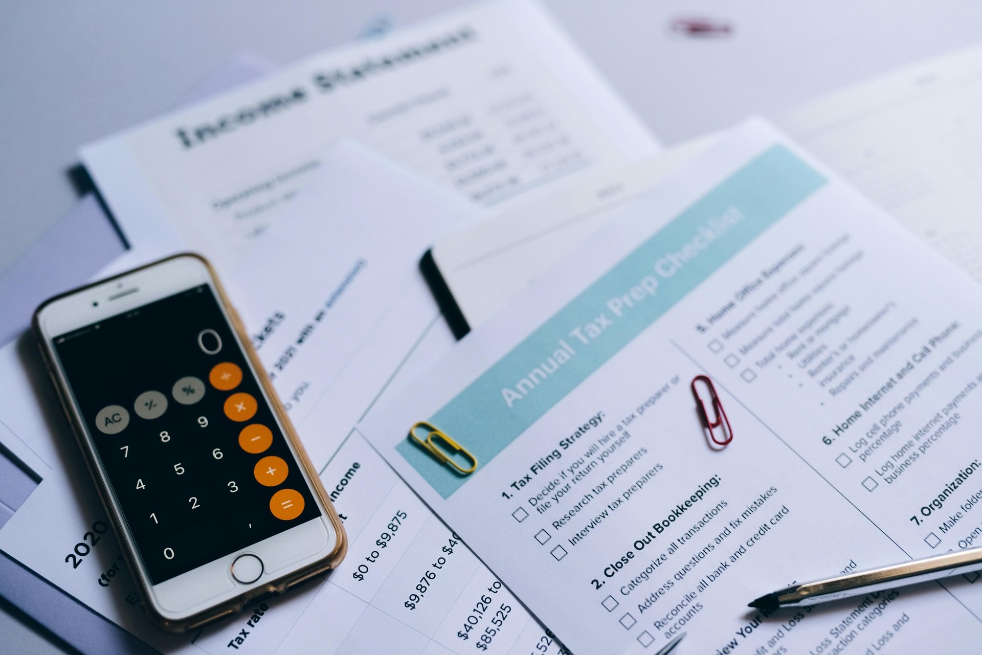 Person reviewing documents with calculator and laptop.
