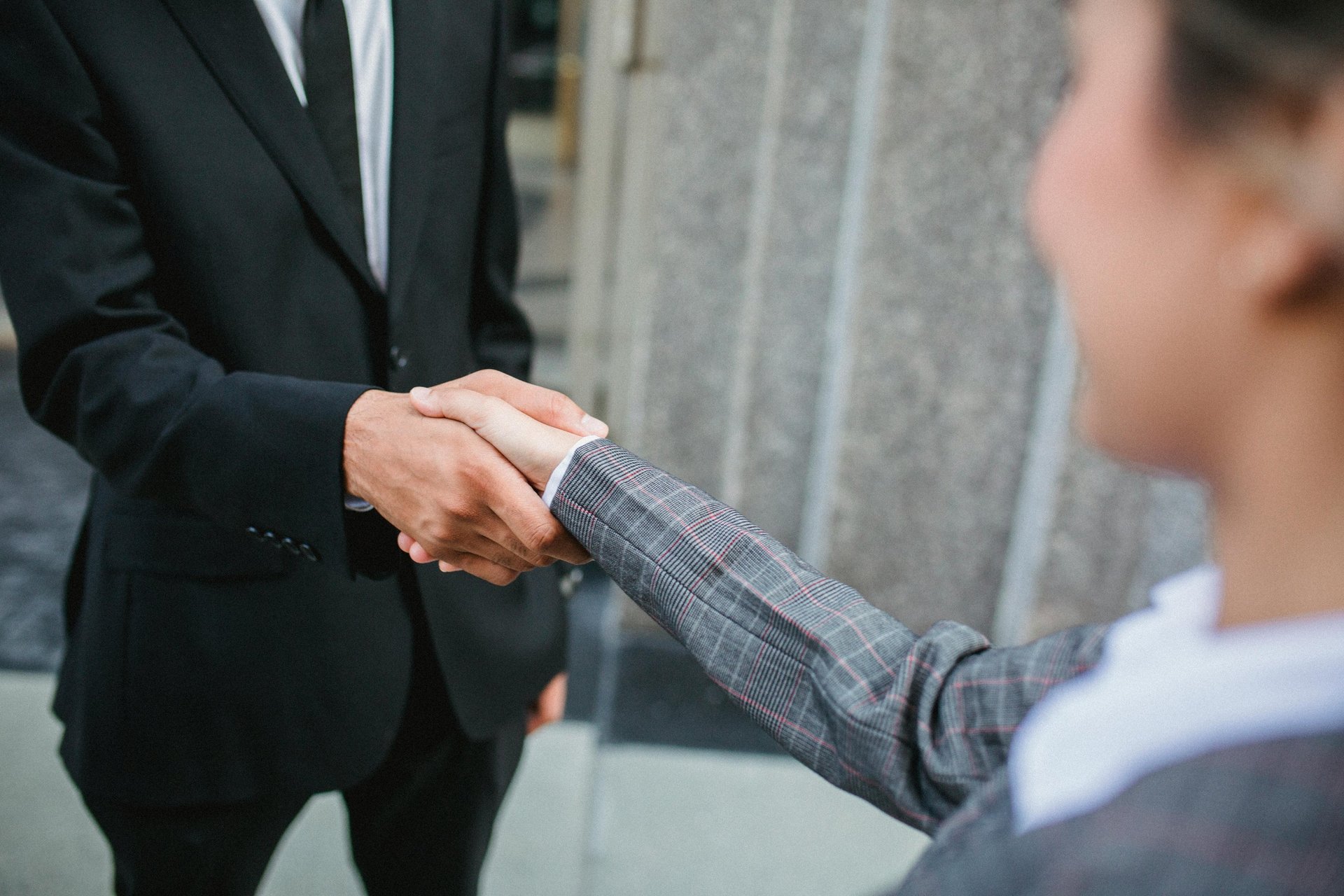 two people shaking hands in front of a laptop