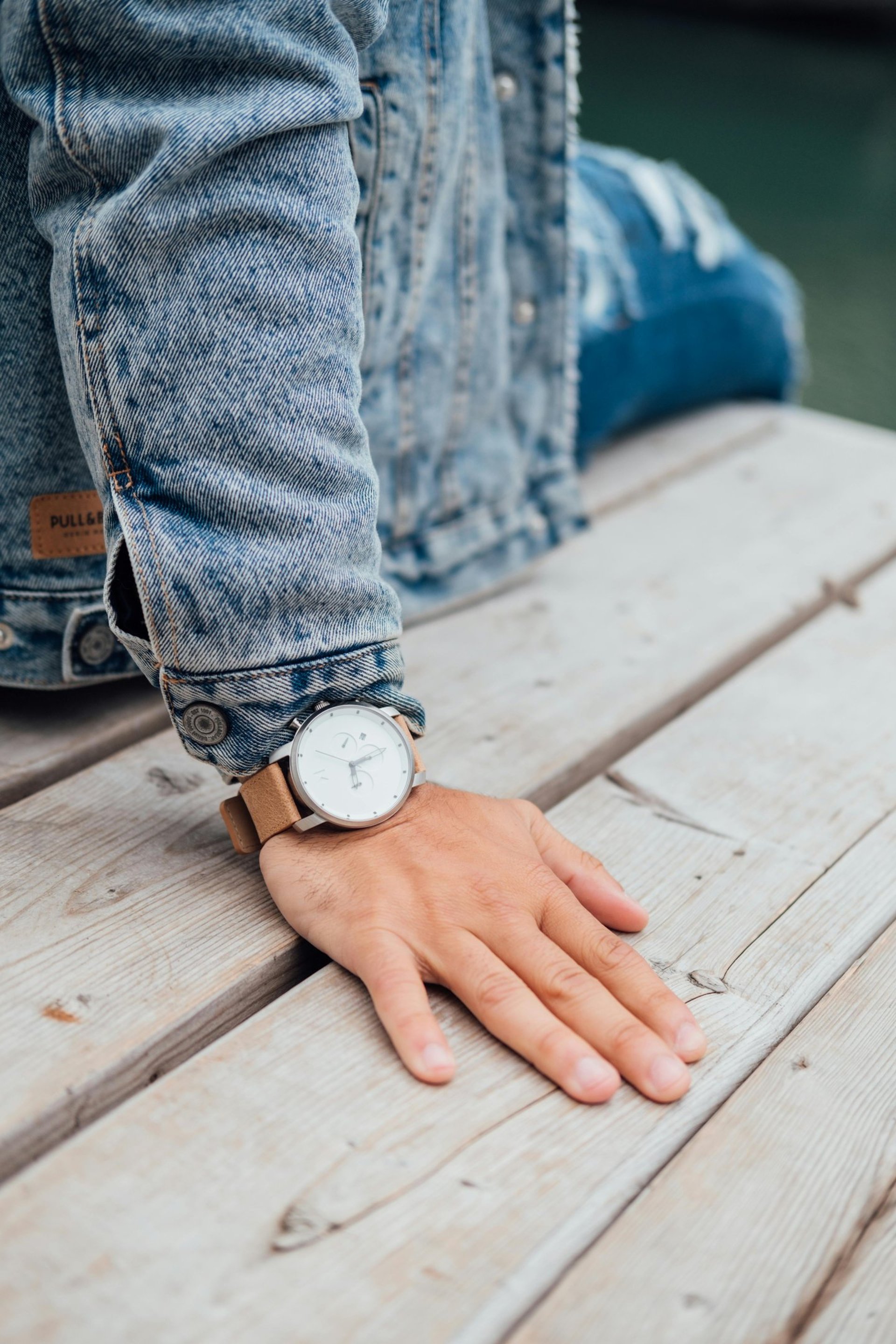 person wearing silver round analog watch with black leather strap